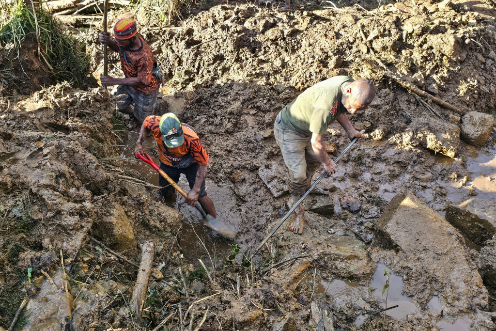 People dig through debris at the site of a landslide in Yambali village in the region of Maip Mulitaka, in Enga Province, Papua New Guinea.