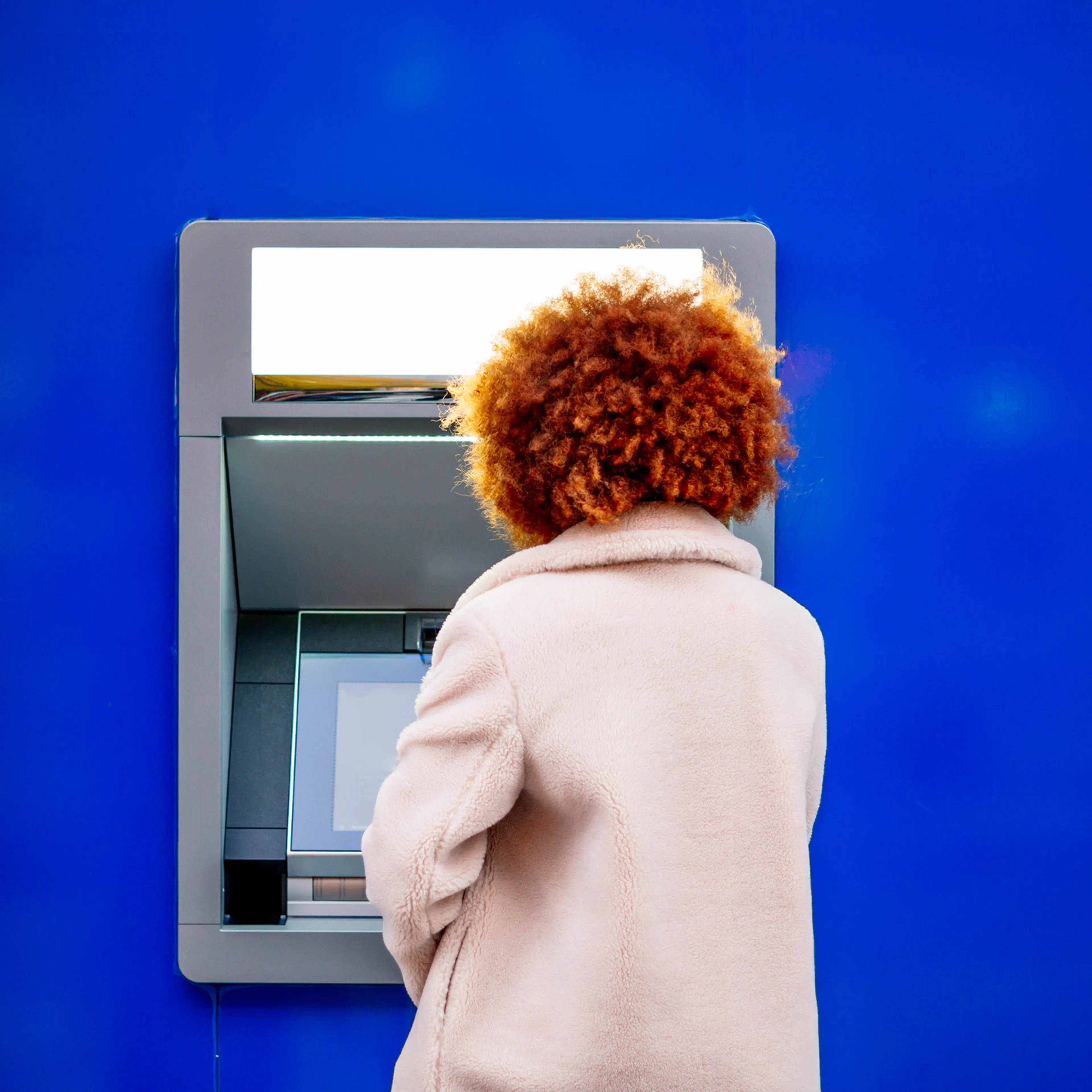 Mid adult woman with afro hair using kiosk in city