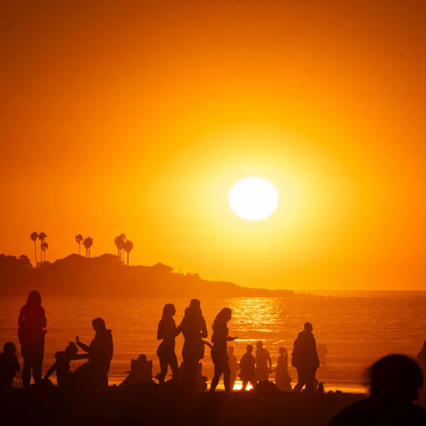Crowds flock to the coast at La Jolla Shores beach as smoke from the Los Angeles fires settles on the Pacific Ocean at sunset on Jan. 10, 2025 in San Diego, California.