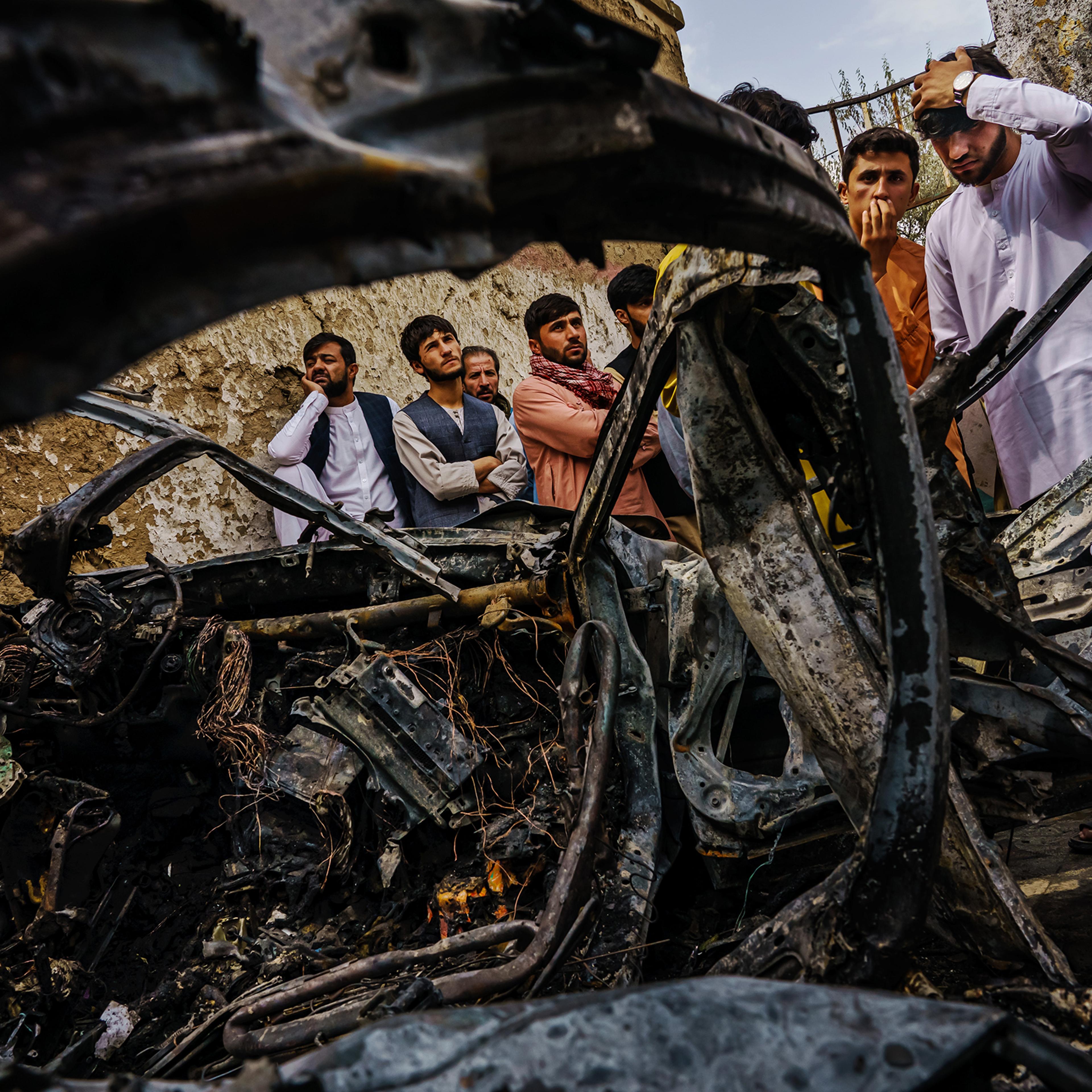 Relatives and neighbors of the Ahmadi family gathered on Aug. 30, 2021, around the incinerated husk of a vehicle targeted a day earlier by the American drone strike.