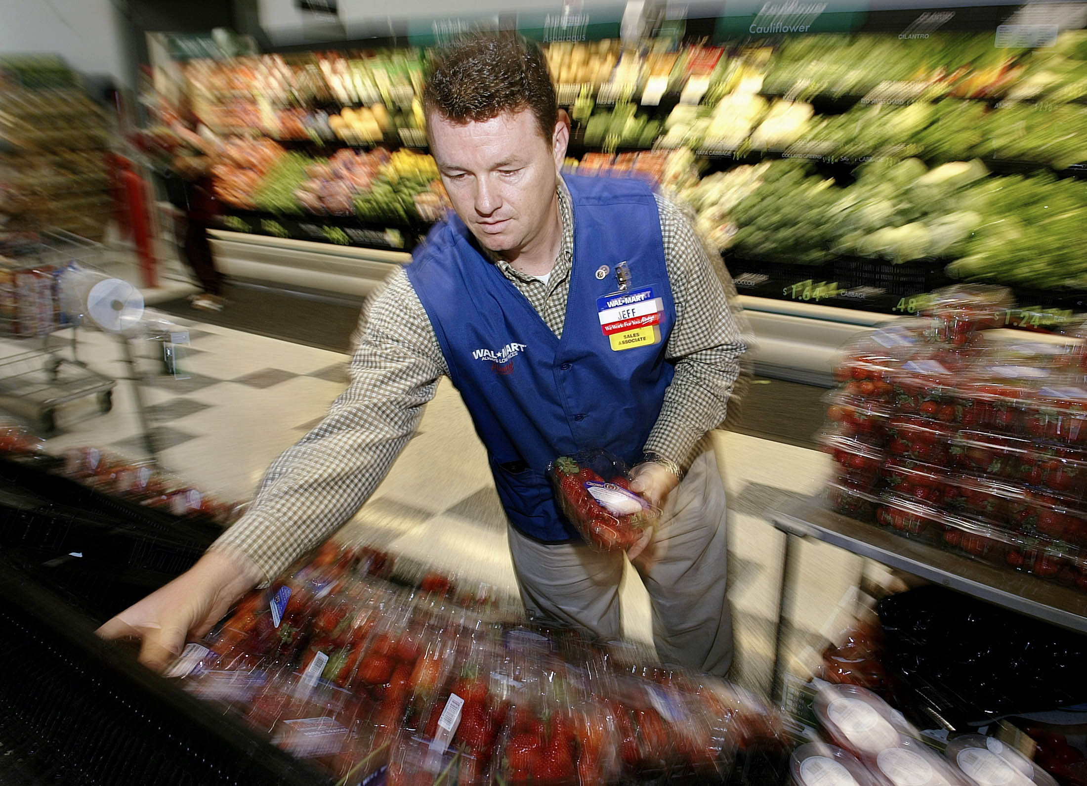 Wal-Mart Associate Jeff Parker stocks produce at store #100 in Bentonville, Arkansas on July 2, 2003.
