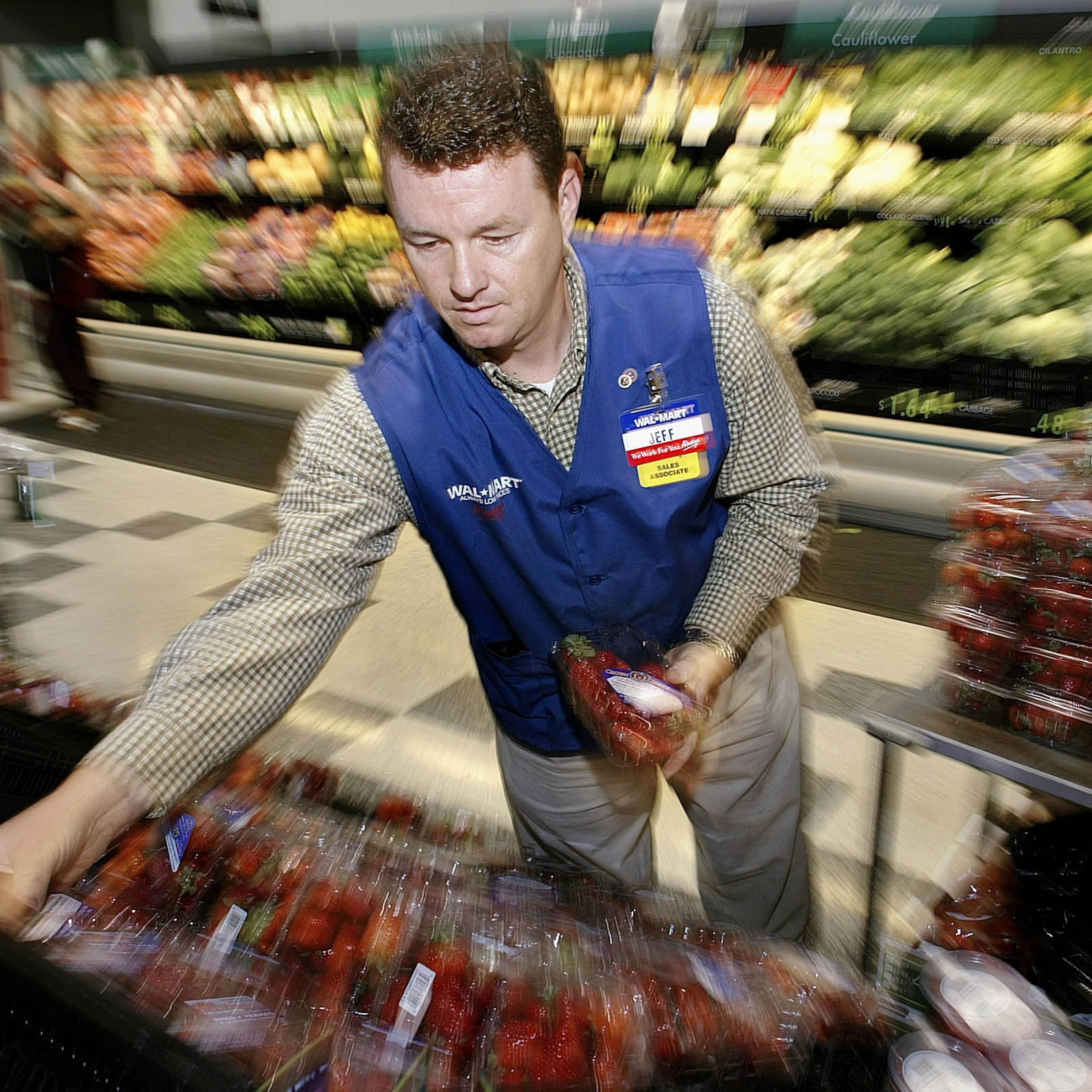 Wal-Mart Associate Jeff Parker stocks produce at store #100 in Bentonville, Arkansas on July 2, 2003.