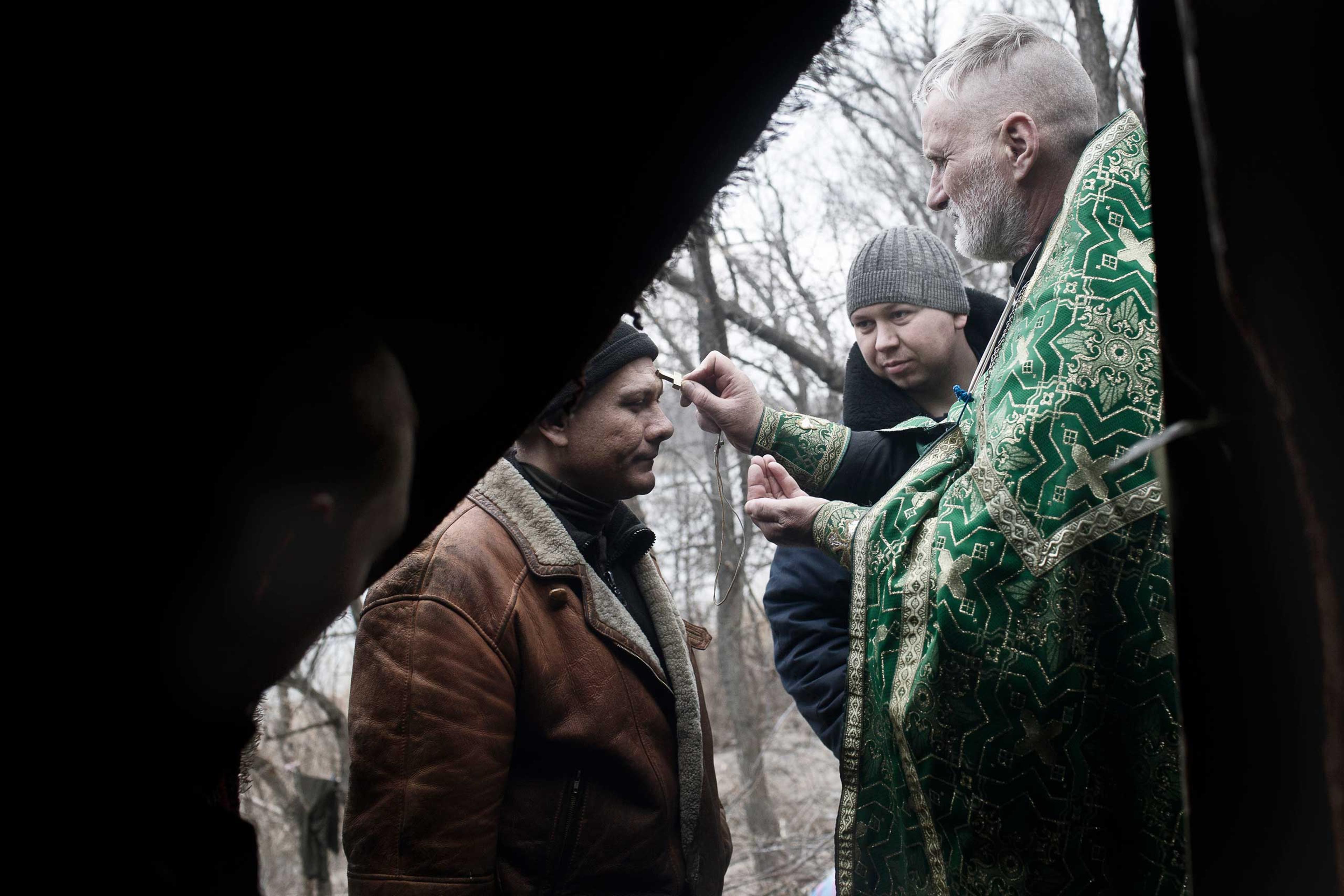 A Ukrainian Orthodox priest ministers to a volunteer member of the Aidar Battalion, a volunteer group fighting against Russian separatists in Shastya in the restive region of Luhansk, eastern Ukraine, Feb. 8, 2015.