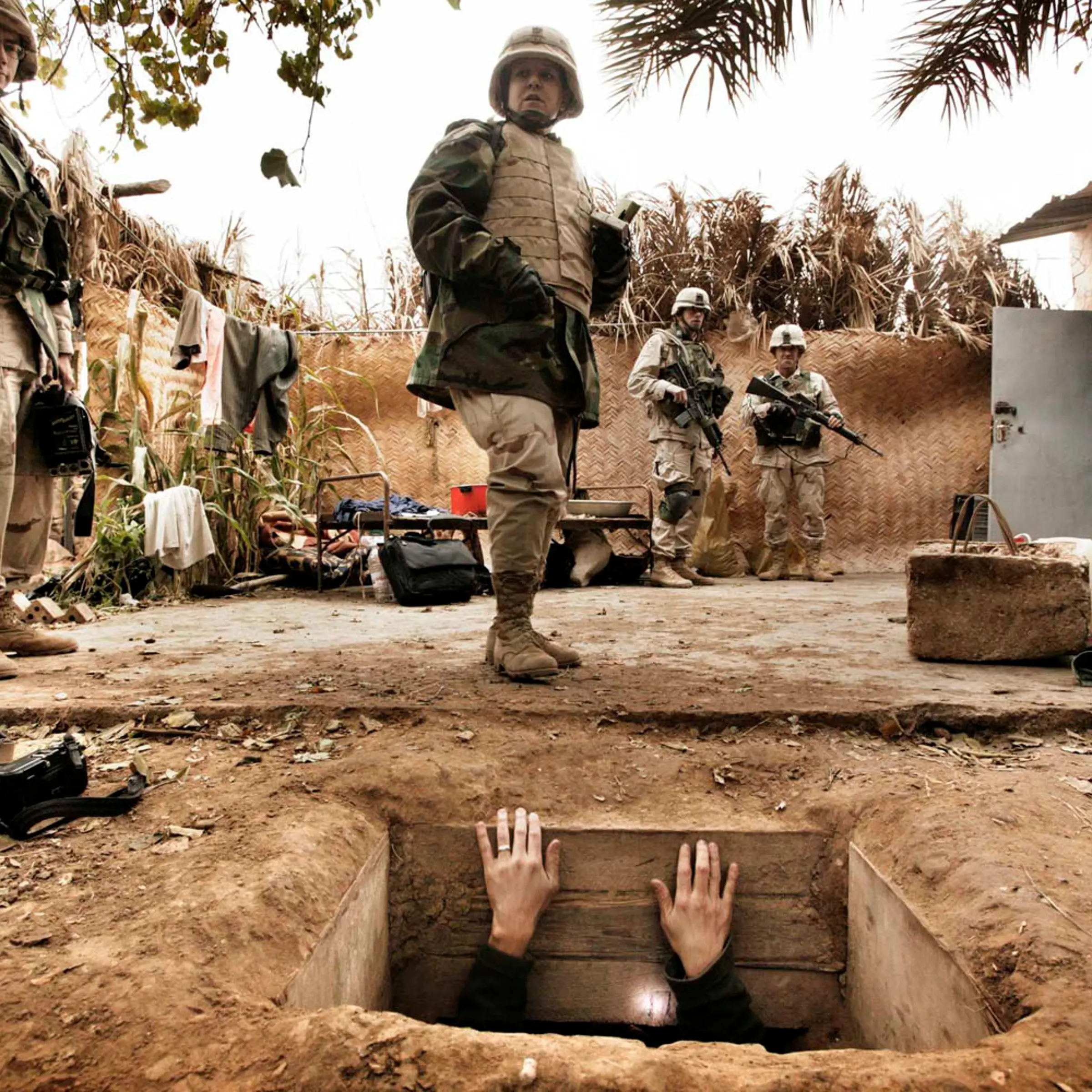 A journalist climbs out of the hole where toppled dictator Saddam Hussein was captured in Ad Dawr. Iraq’s defeated leader raised his arms out of his “rat hole” and said he was Saddam Hussein and that he wanted to negotiate. Iraq, December 15, 2003