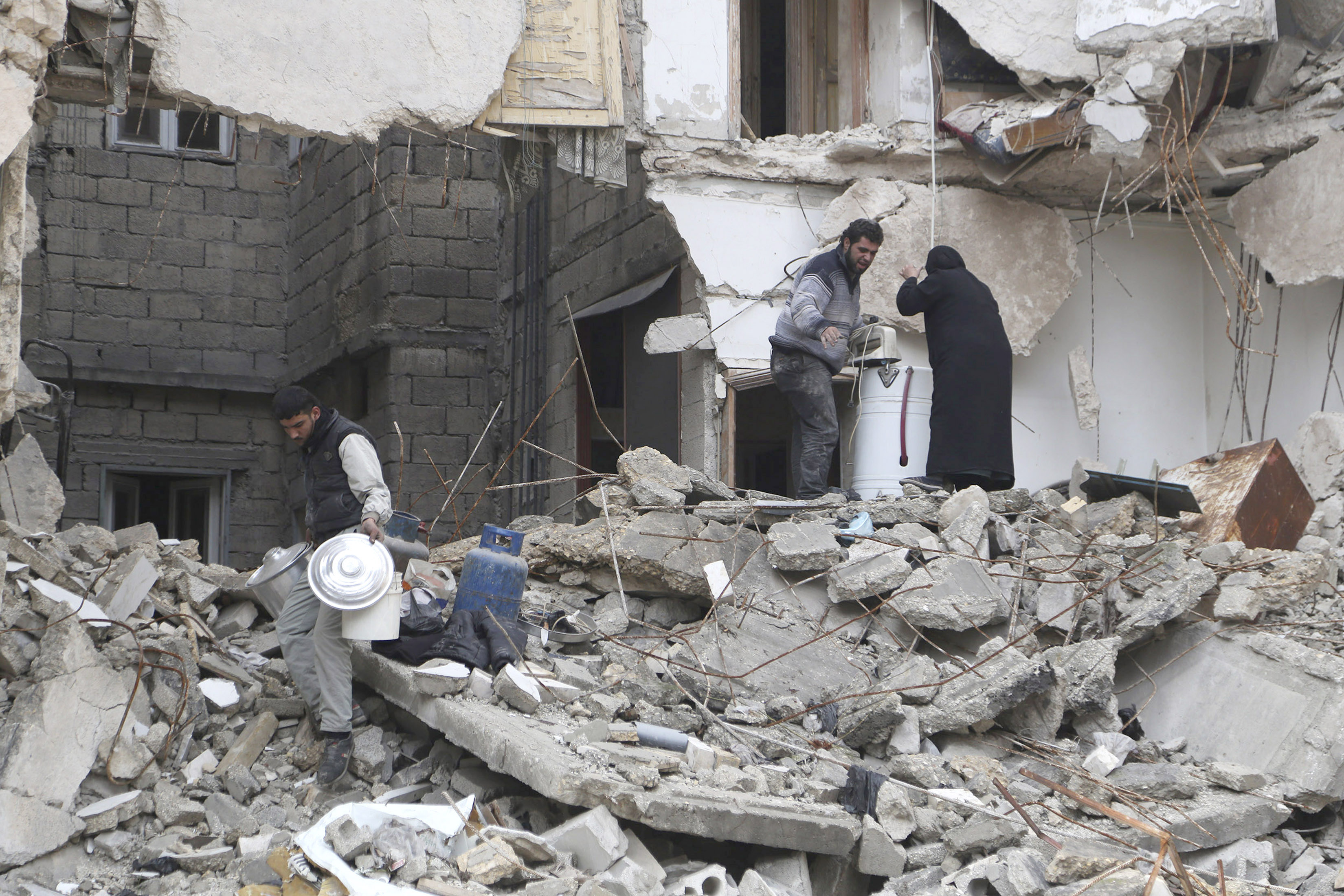 Residents look for belongings amid debris of a collapsed building in Aleppo