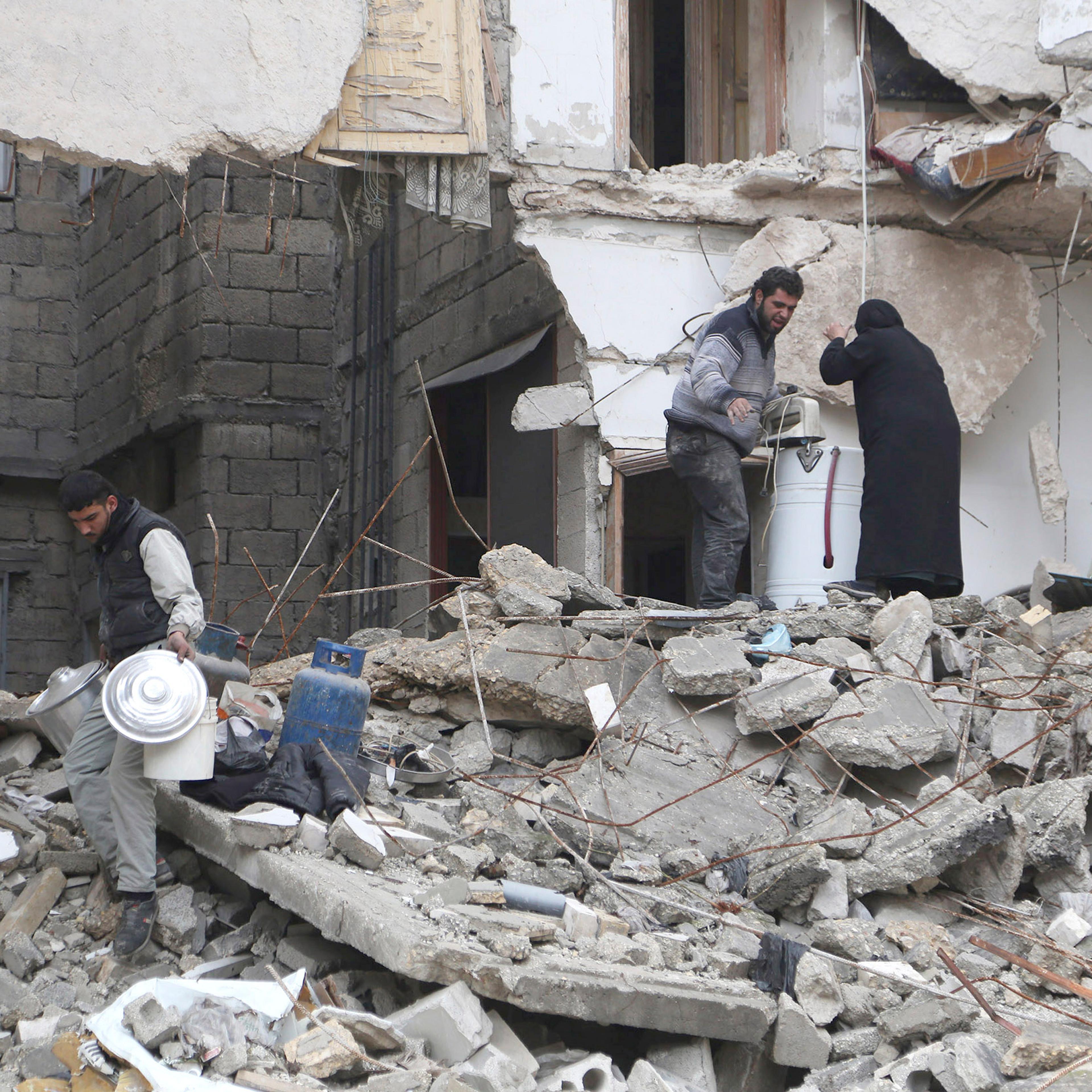Residents look for belongings amid debris of a collapsed building in Aleppo
