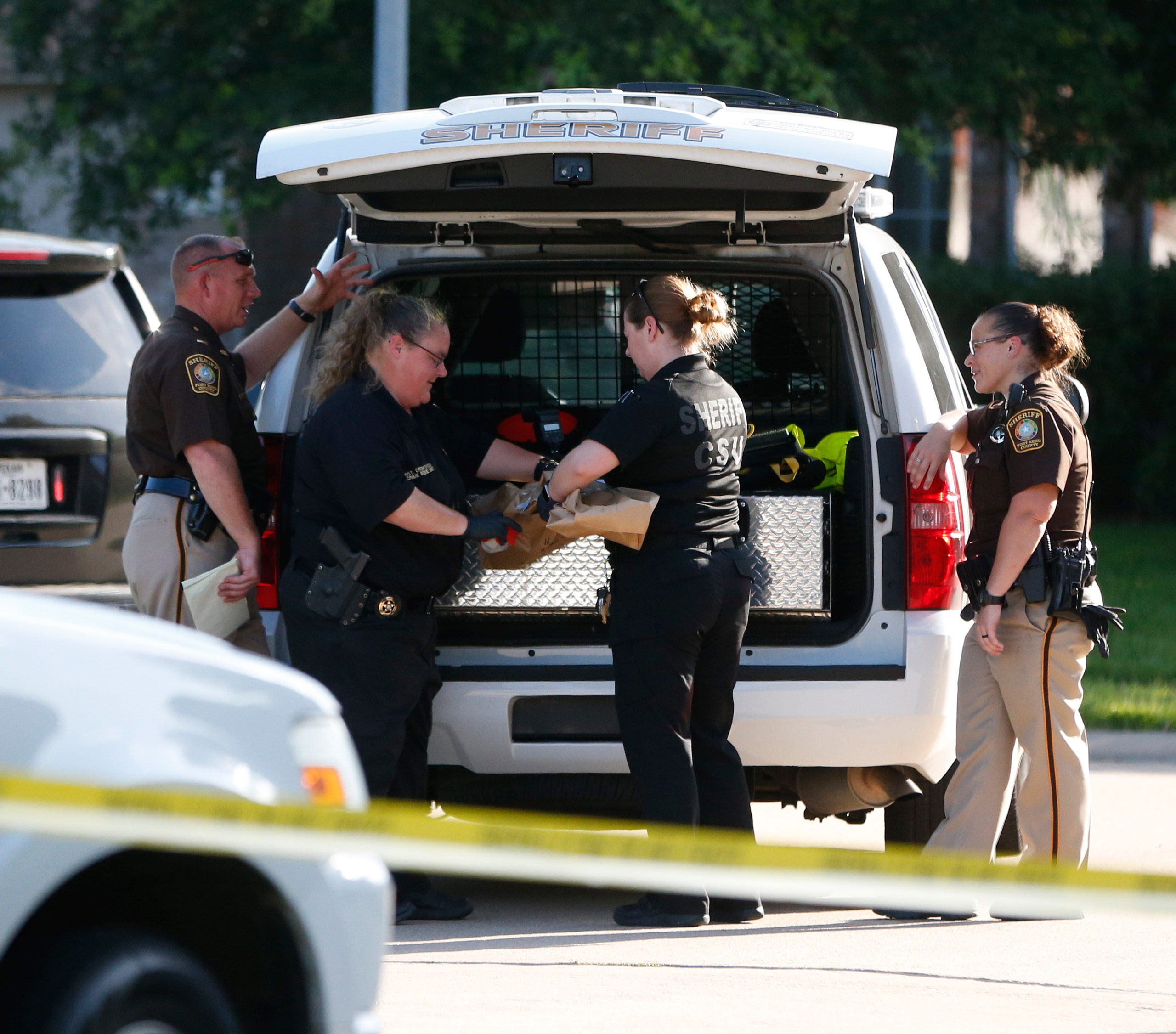 In this Friday, June 24, 2016 photo, Fort Bend County Sheriffs department crime scene members bag a gun for evidence in a shooting at Blanchard Grove and Remson Hollow in Katy, Texas. Officials said a woman shot her two adult daughters - killing one of t