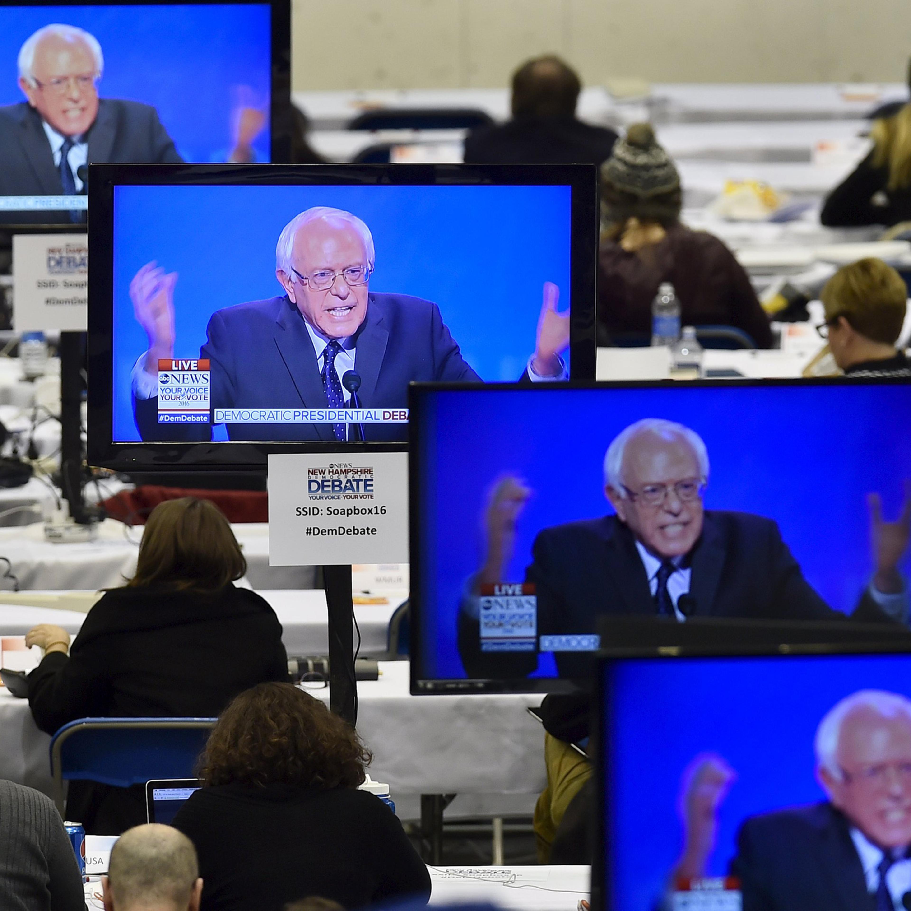 U.S. Democratic presidential candidate Bernie Sanders appears on television screens in the media work-room during the Democratic presidential candidates debate at Saint Anselm College in Manchester, New Hampshire December 19, 2015. REUTERS/Gretchen Ertl