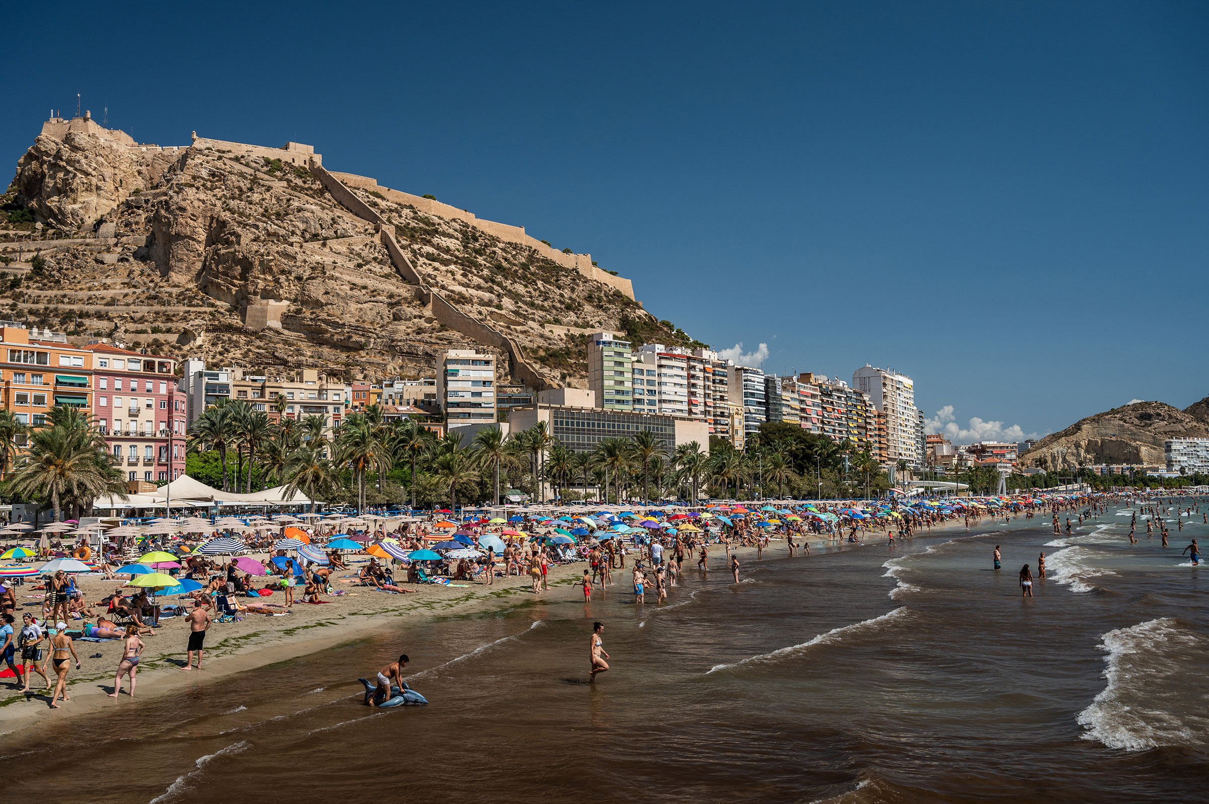 Tourists and locals crowd El Postiguet Beach on a hot August day in Alicante, Spain. 