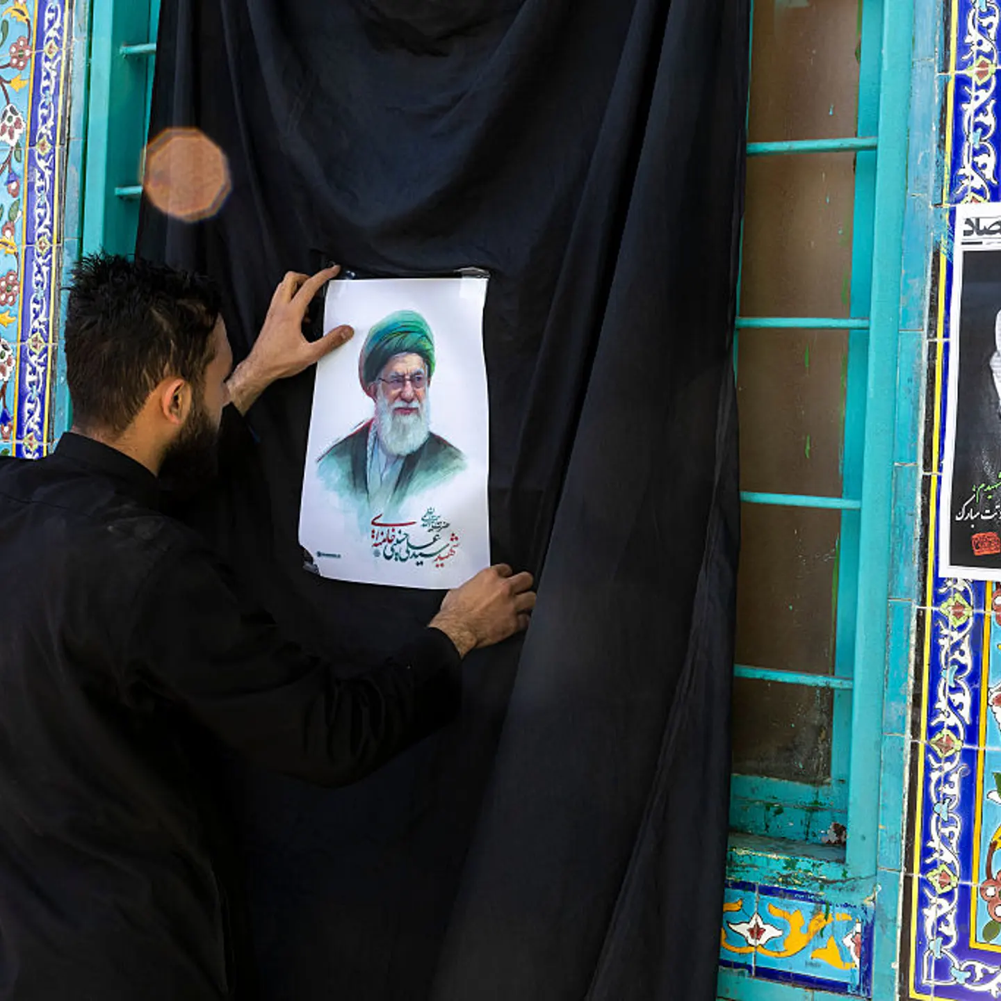 A man puts up a leaflet featuring an portrait of Ayatollah Ali Khamenei in Tehran, Iran on March 5, 2026.