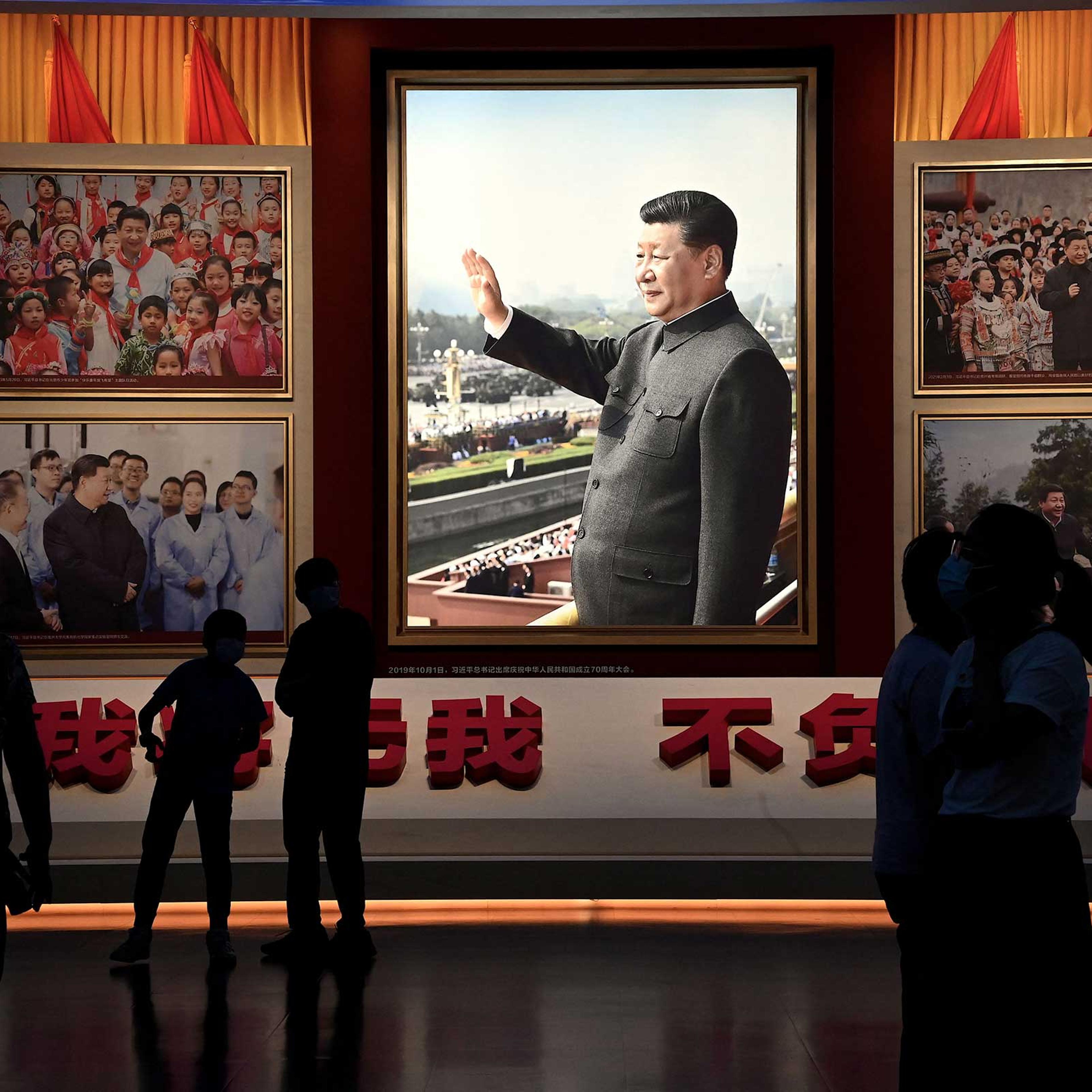 People stand in front of images of Chinese President Xi Jinping at the Museum of the Communist Party of China in Beijing on September 4, 2022.