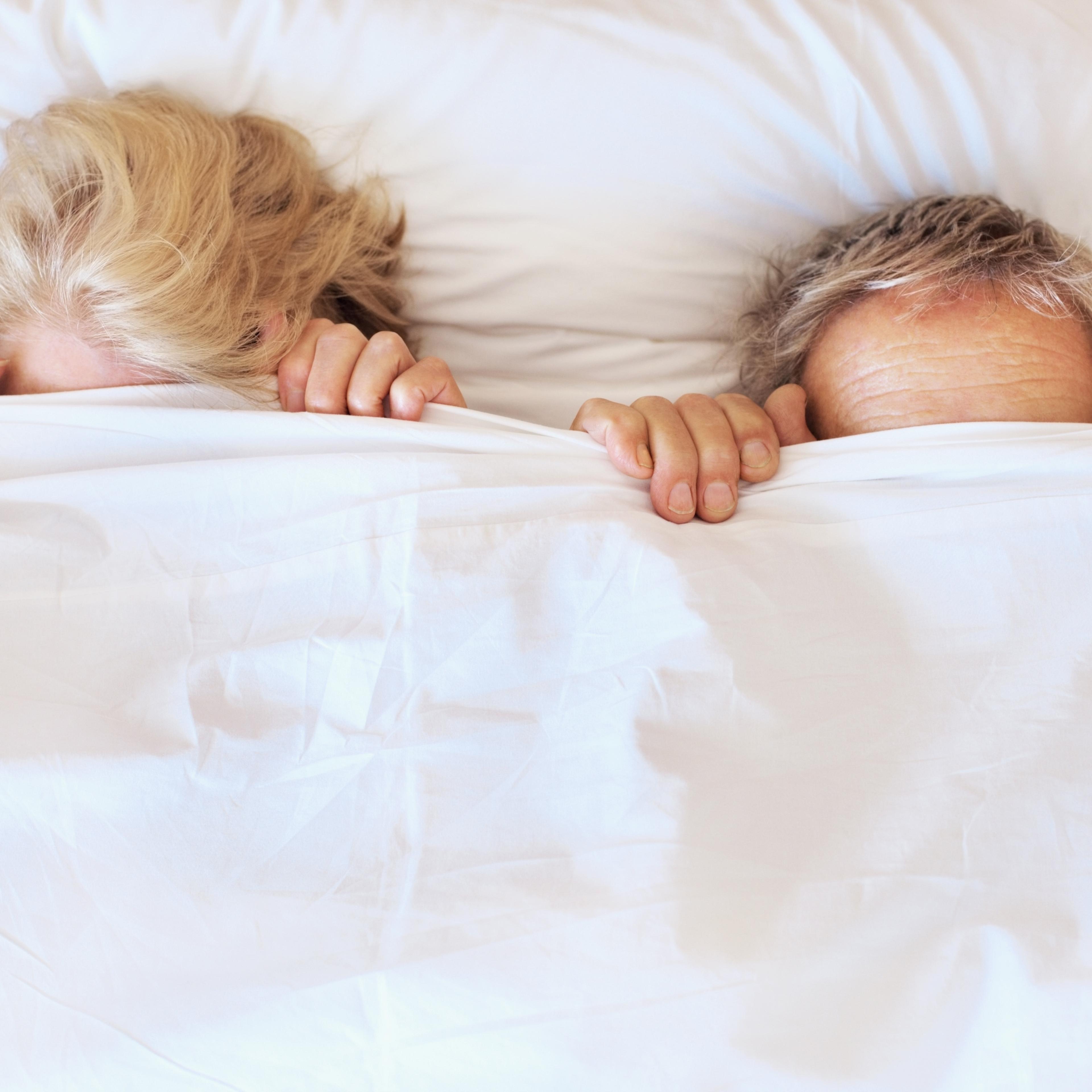 Couple in bed with a bedsheet covering faces TIME health stock