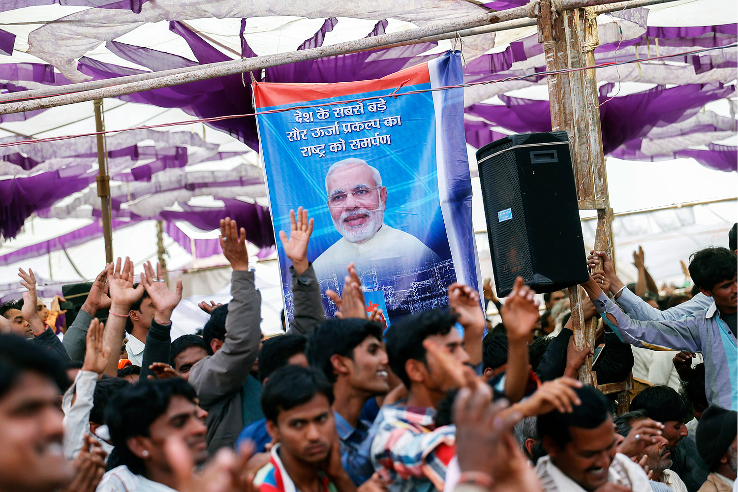 Supporters cheer beneath a poster featuring Narendra Modi at a rally near Bhagwanpura, Madhya Pradesh, India, on Feb. 26, 2014