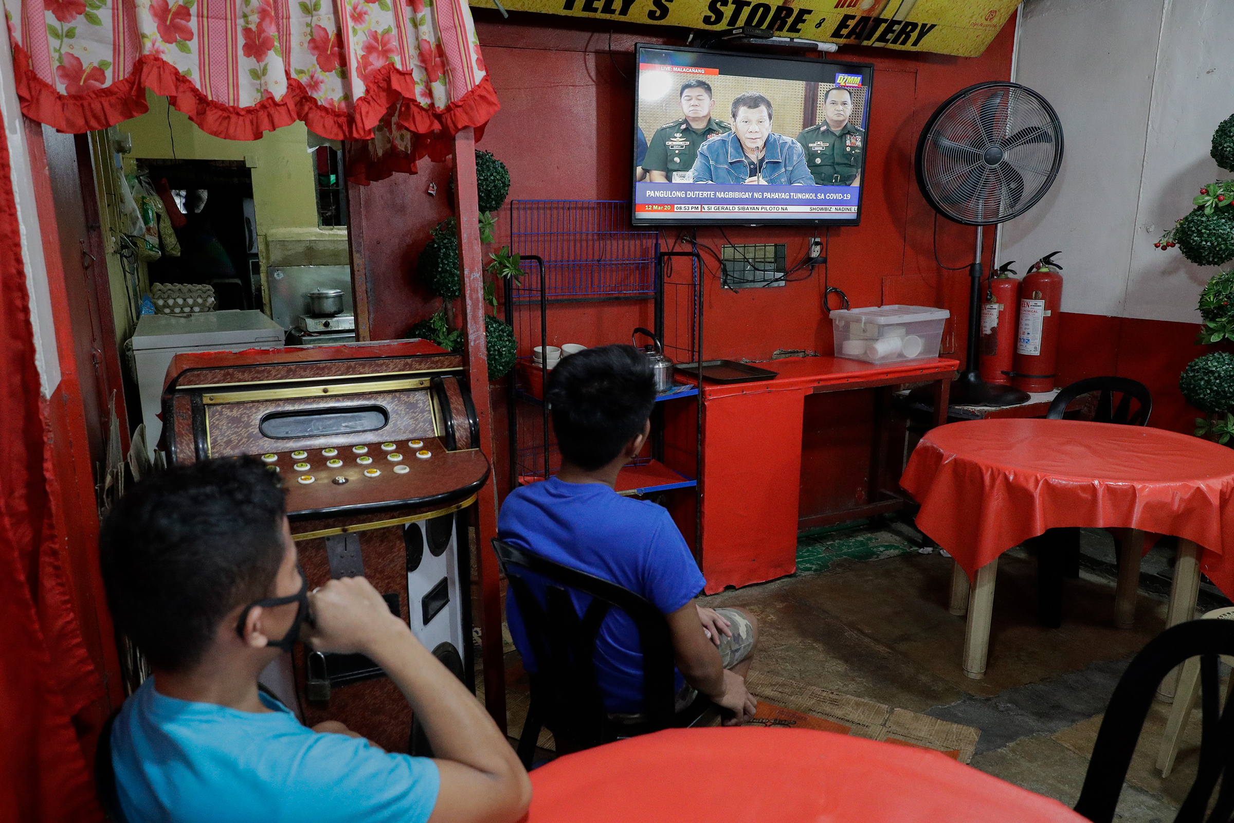 Restaurant workers watch Philippine President Rodrigo Duterte as he delivers a speech on TV about the COVID-19 virus situation in metropolitan Manila on March 12, 2020