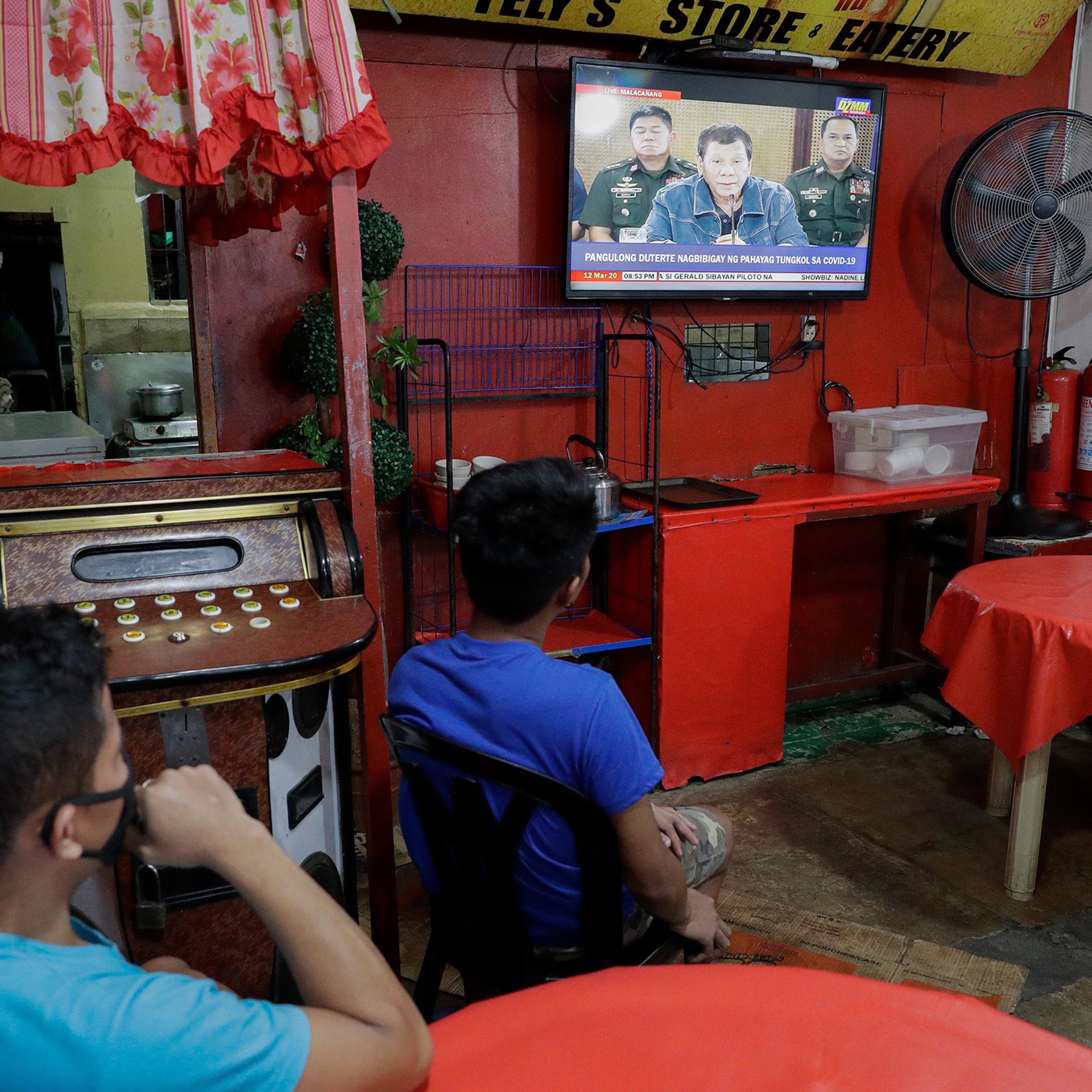 Restaurant workers watch Philippine President Rodrigo Duterte as he delivers a speech on TV about the COVID-19 virus situation in metropolitan Manila on March 12, 2020
