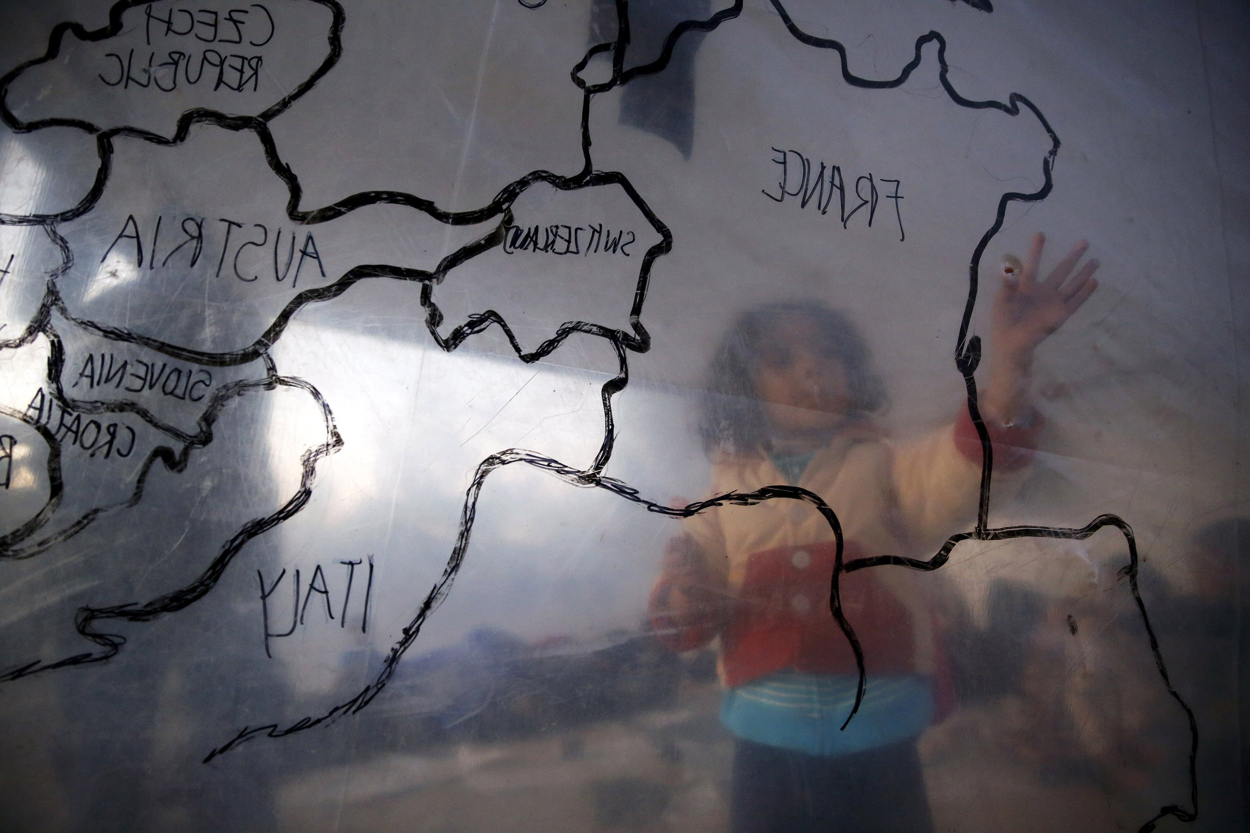 A refugee child looks at a map of Europe at a camp on the Greek island of Lesbos