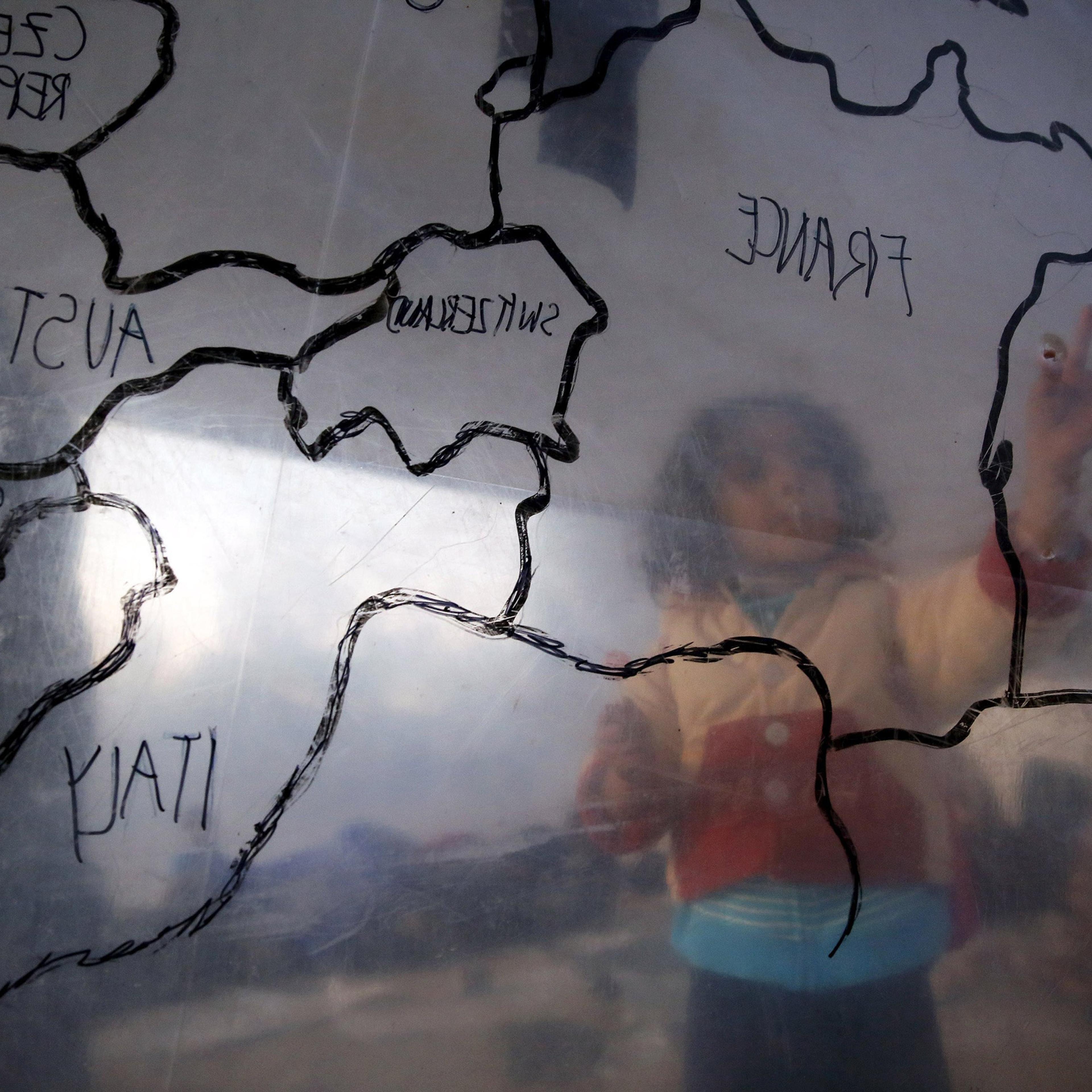 A refugee child looks at a map of Europe at a camp on the Greek island of Lesbos