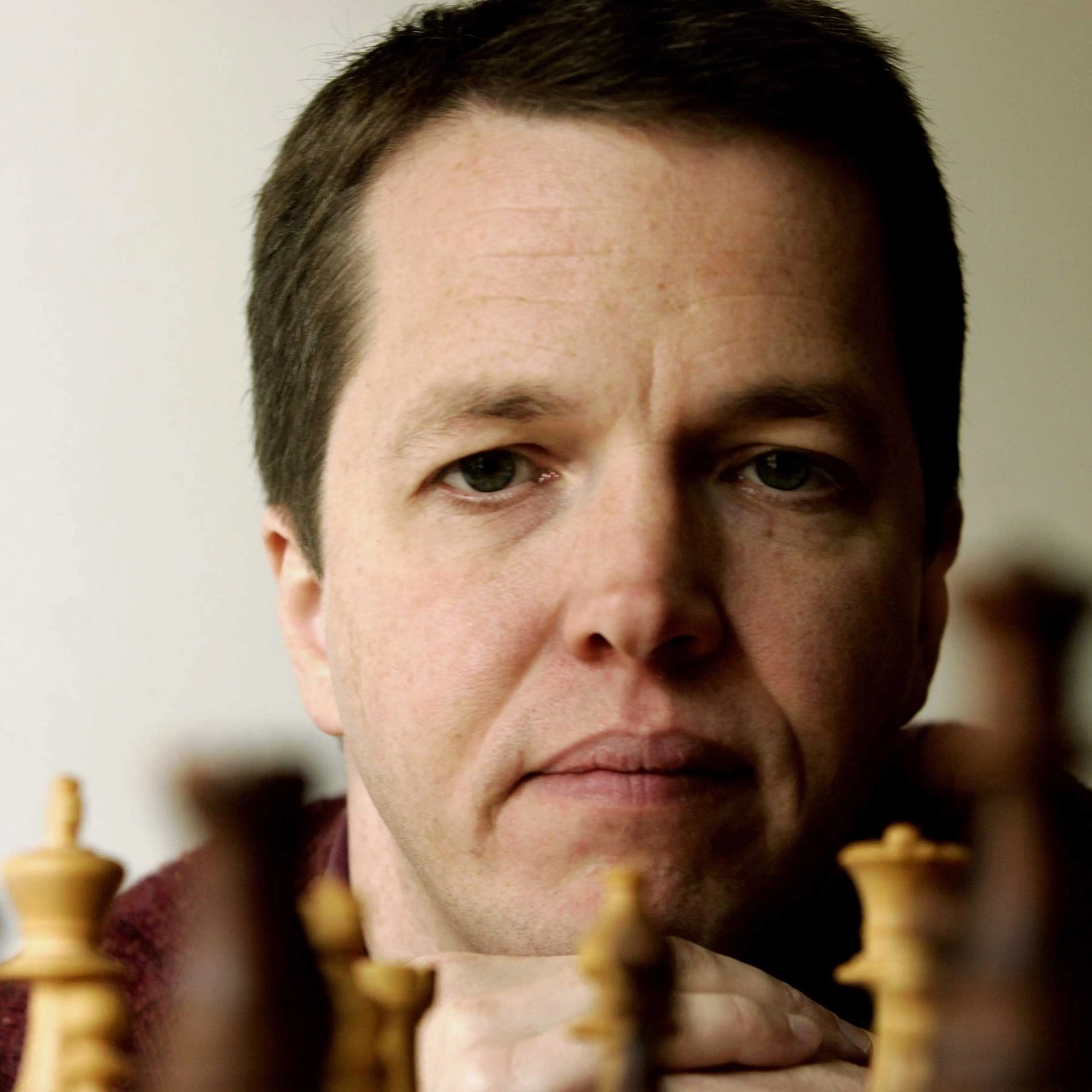 British former World Chess Championhip finalist Nigel Short looks at a chess board in his home in Athens November 4, 2005.