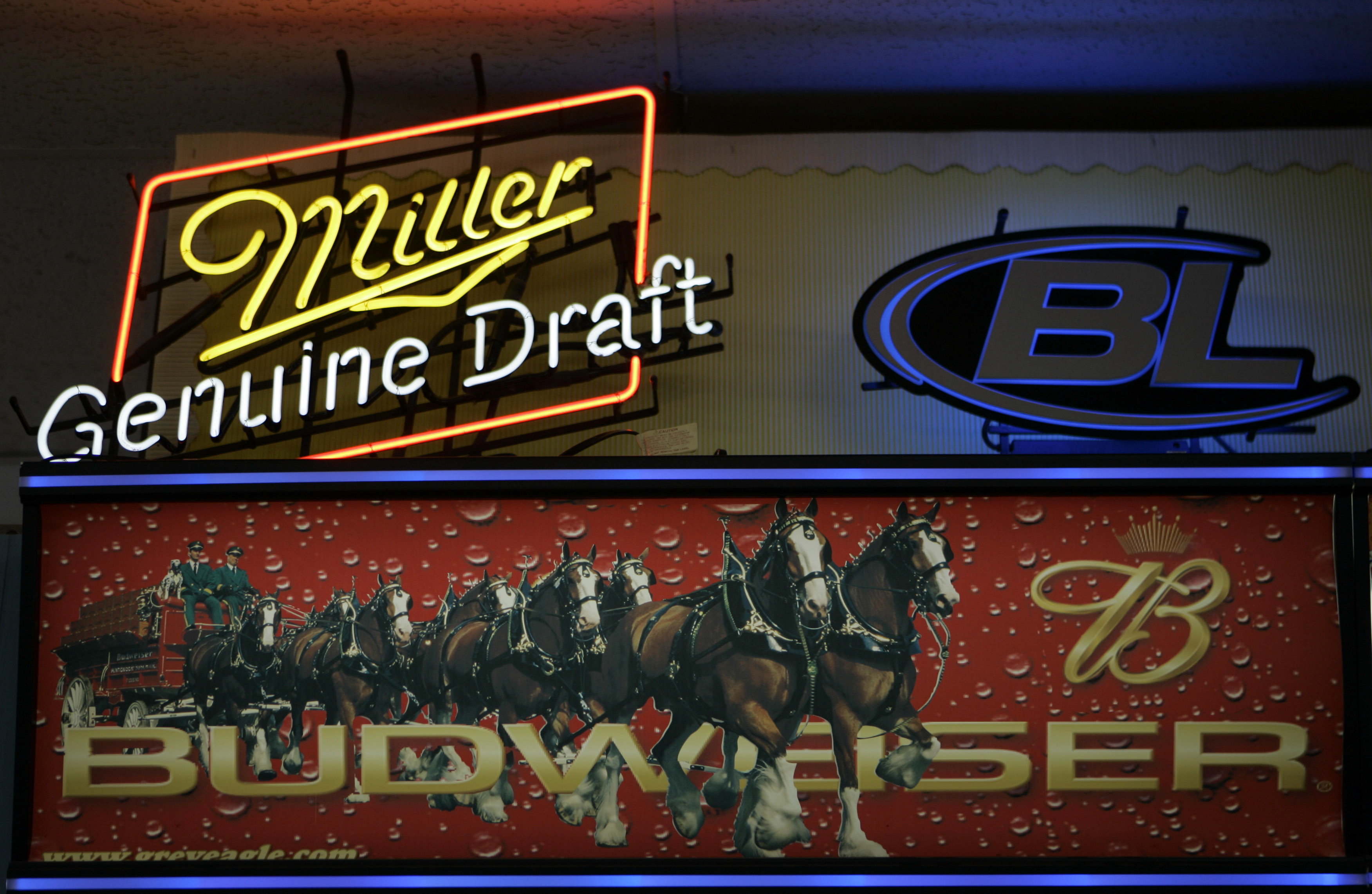Signs for Miller and Anheuser-Busch products above a liquor store cooler in St. Louis, Oct. 23, 2007. Anheuser-Busch InBev, the world's largest beer maker, announced July 20, 2016, that it has reached an agreement with the Justice Department clearing the
