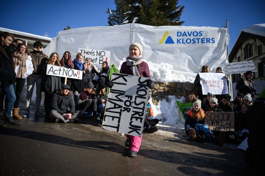 Greta Thunberg holds a placard next to students during a "School strike for climate" at the World Economic Forum