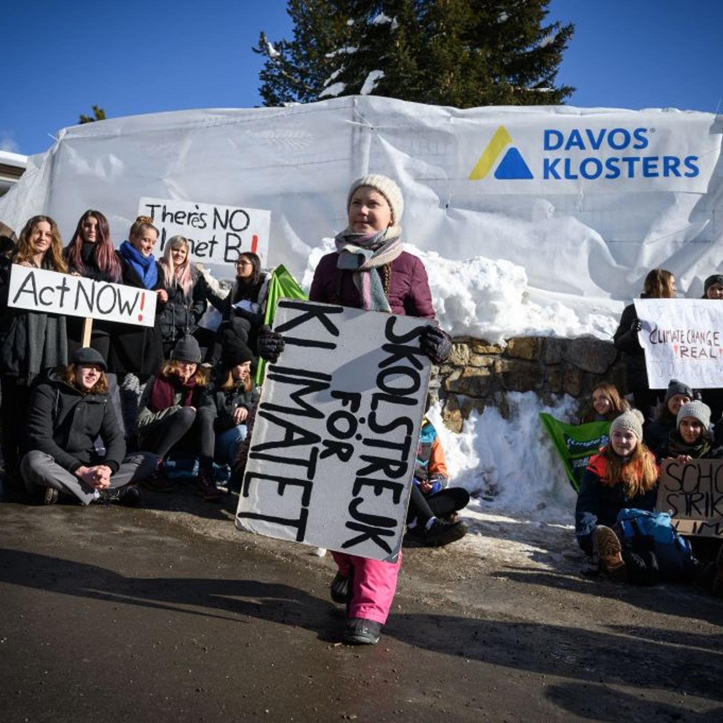 Greta Thunberg holds a placard next to students during a "School strike for climate" at the World Economic Forum