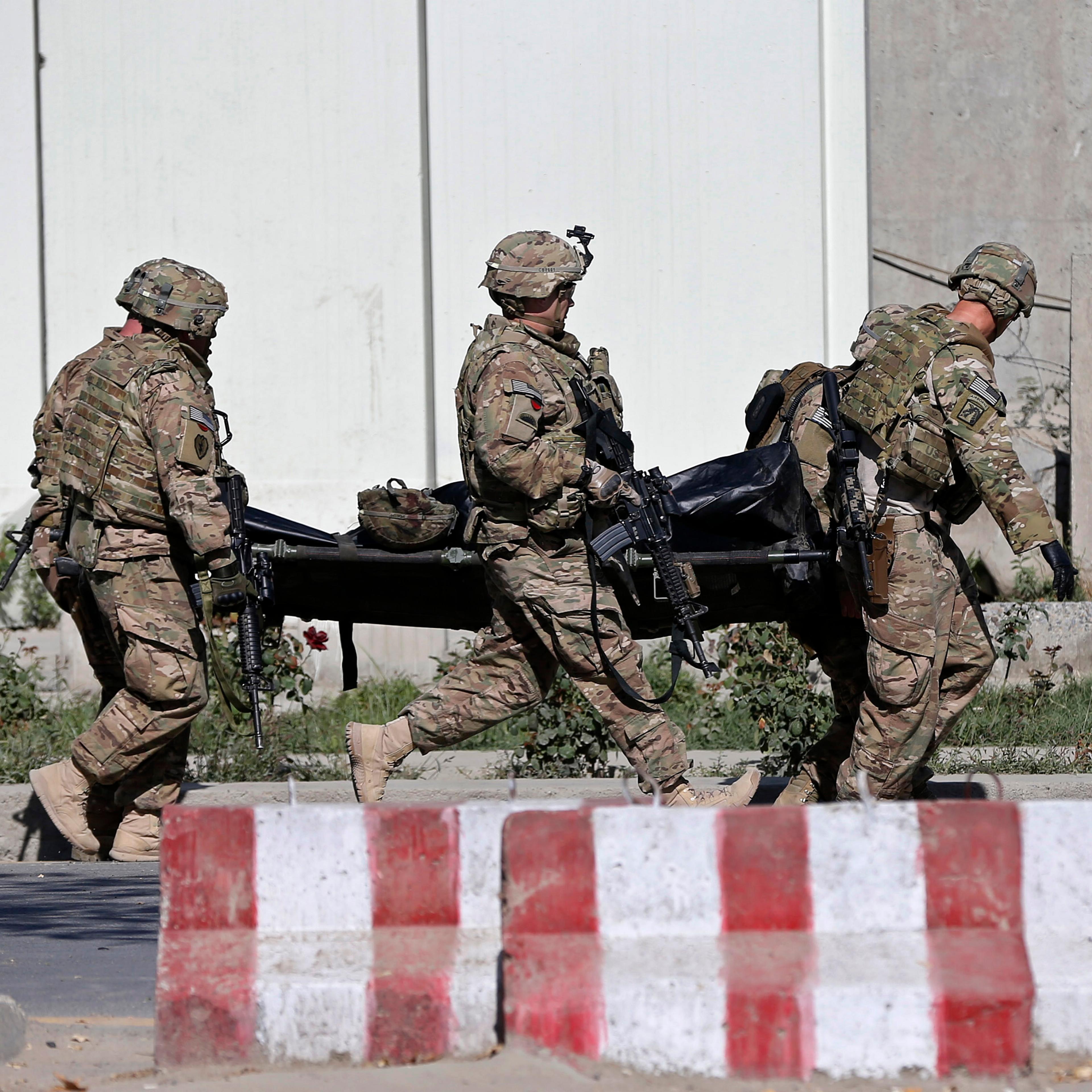 U.S. troops carry the dead body of a member of an international troop at the site of suicide attack in Kabul