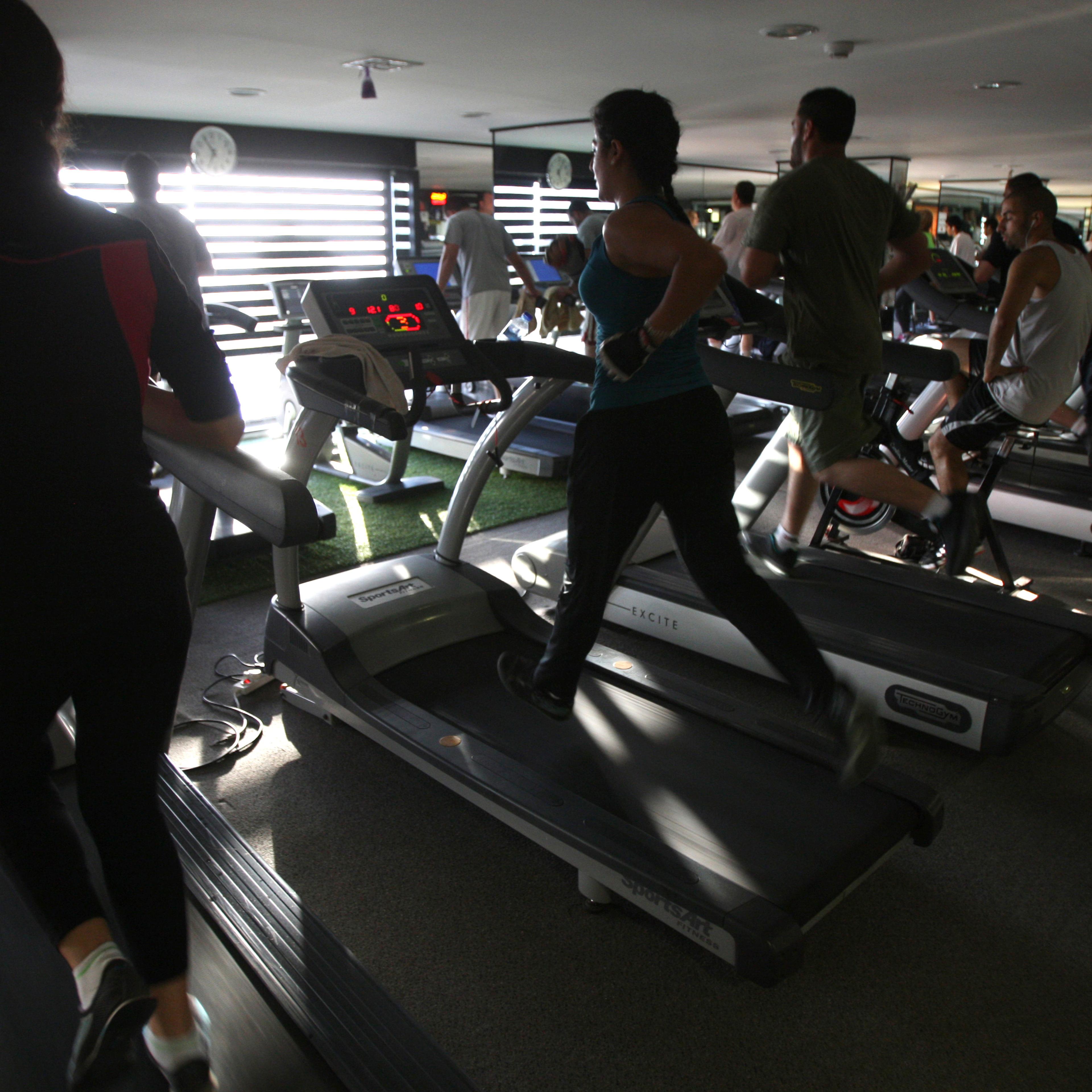 Men and women run on treadmills at a fitness gym in the West Bank city of Ramallah on June 25, 2012.