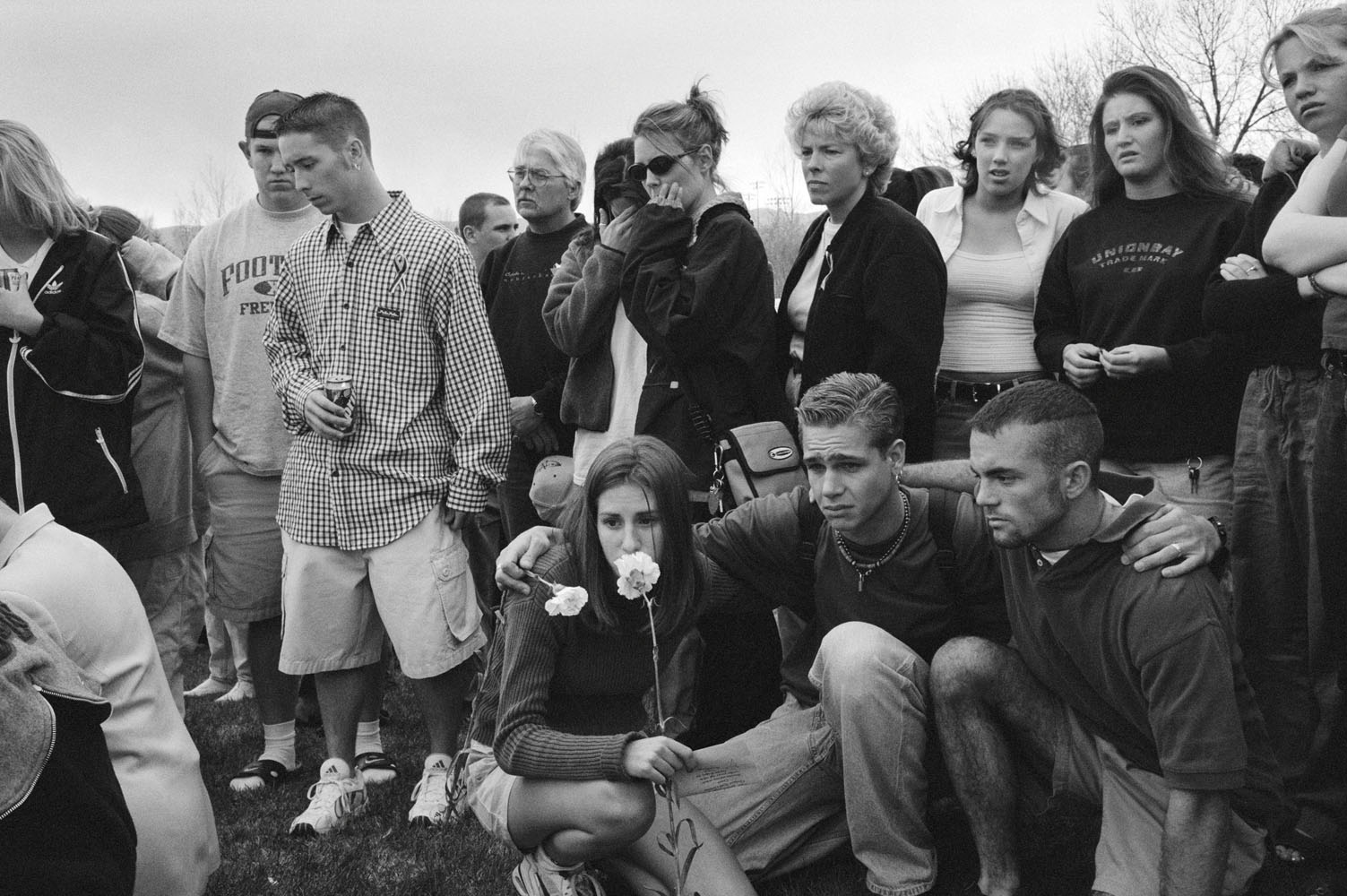 The day after the massacre, Columbine High School students gather outside their school to pray and place flowers on the ground. Many just wander among the tributes crying, trying to make sense of what has happened. 