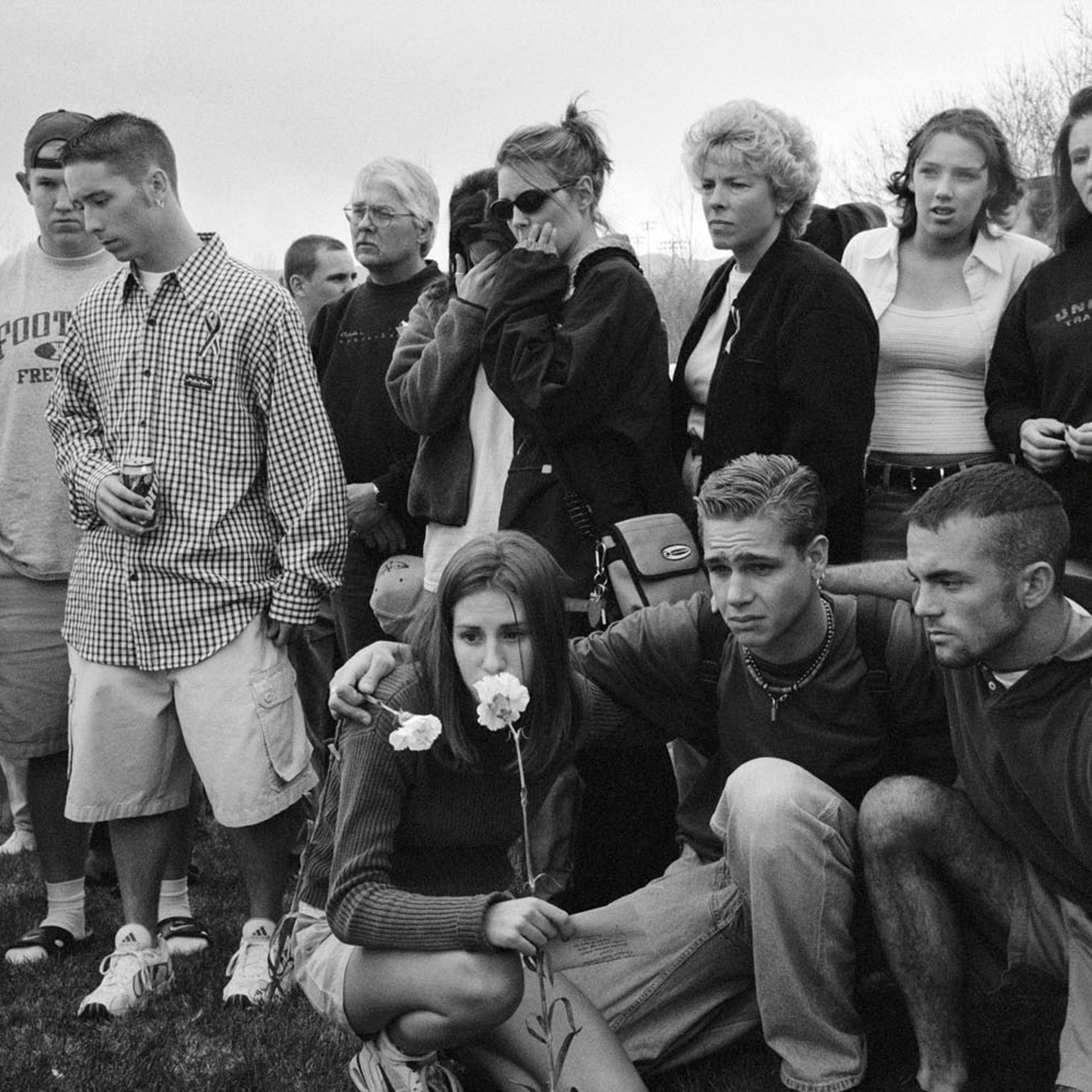 The day after the massacre, Columbine High School students gather outside their school to pray and place flowers on the ground. Many just wander among the tributes crying, trying to make sense of what has happened.