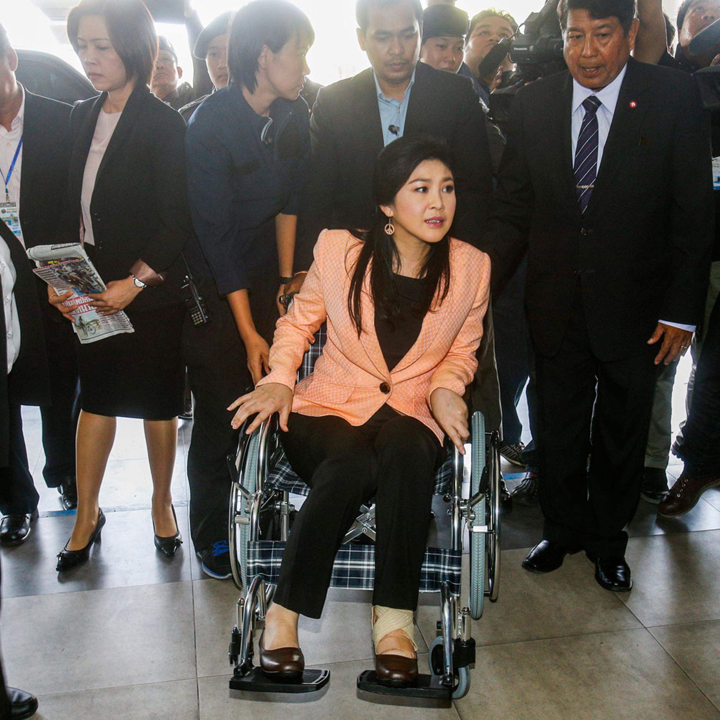 Thailand's Prime Minister Yingluck Shinawatra, center, arrives on a wheelchair at the Royal Police Cadet Academy in Nakorn Pathom province, March 18, 2014.