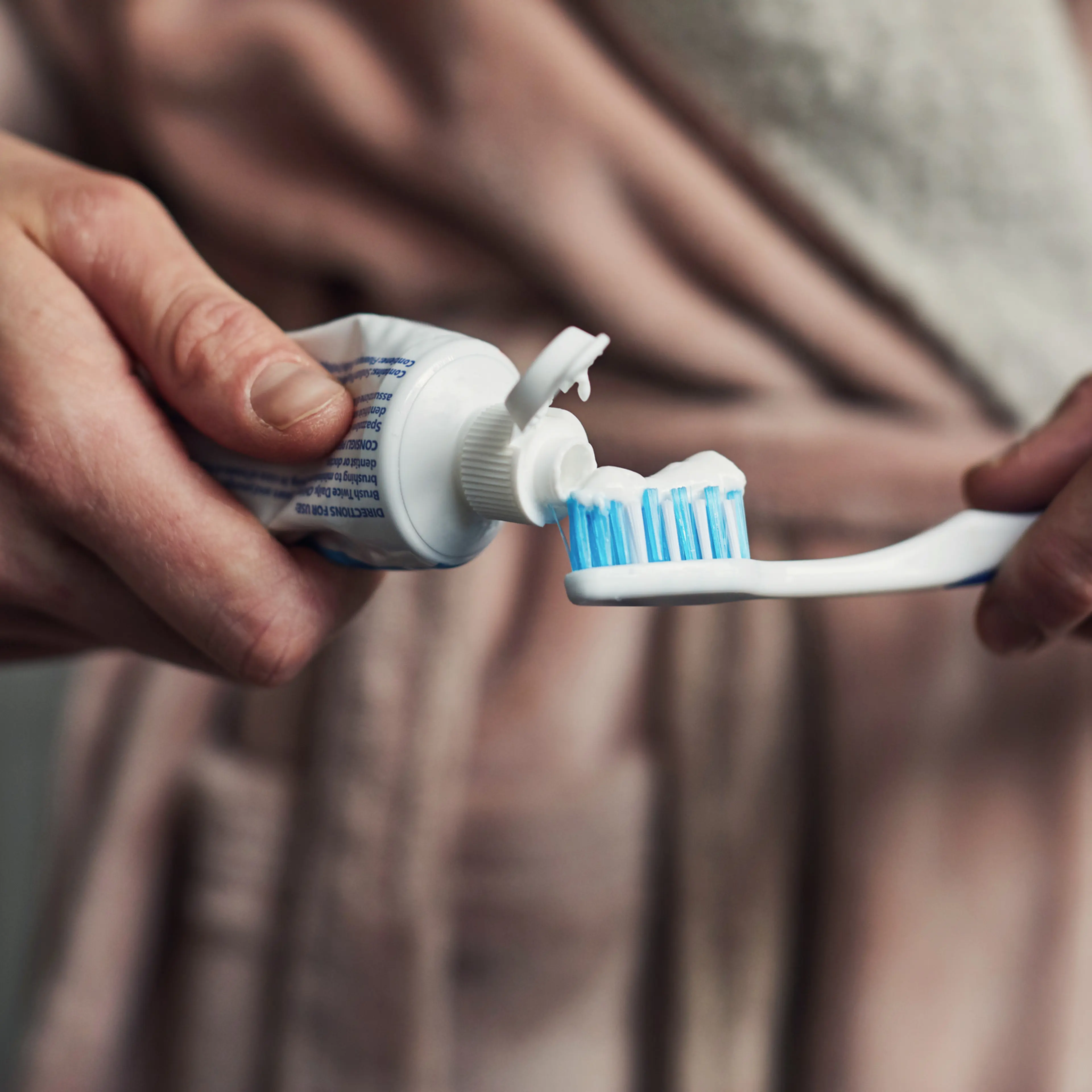 Woman putting toothpaste on a toothbrush