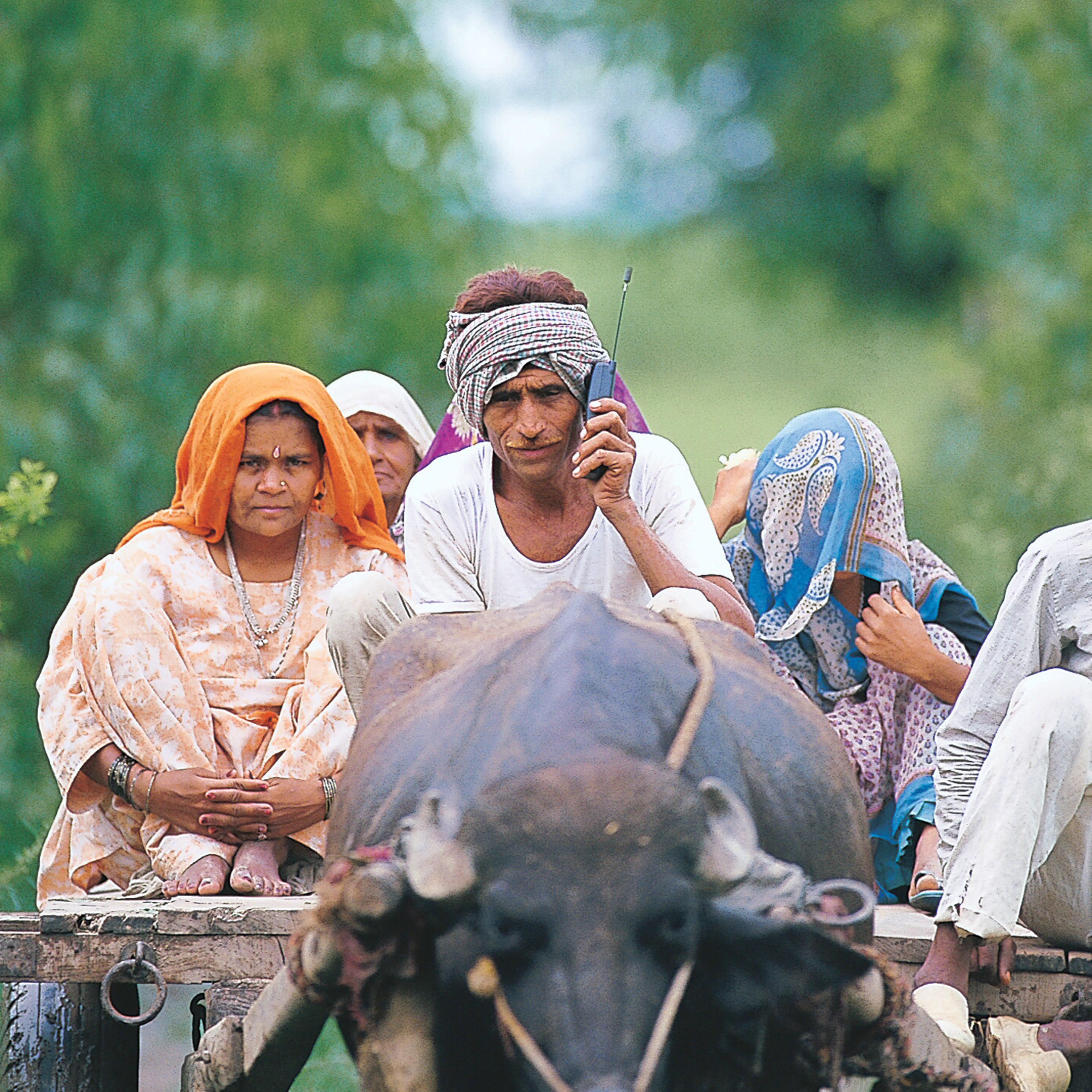 A farmer with his family sitting on a Bullock Cart and talking on a mobile Phone, in Delhi.