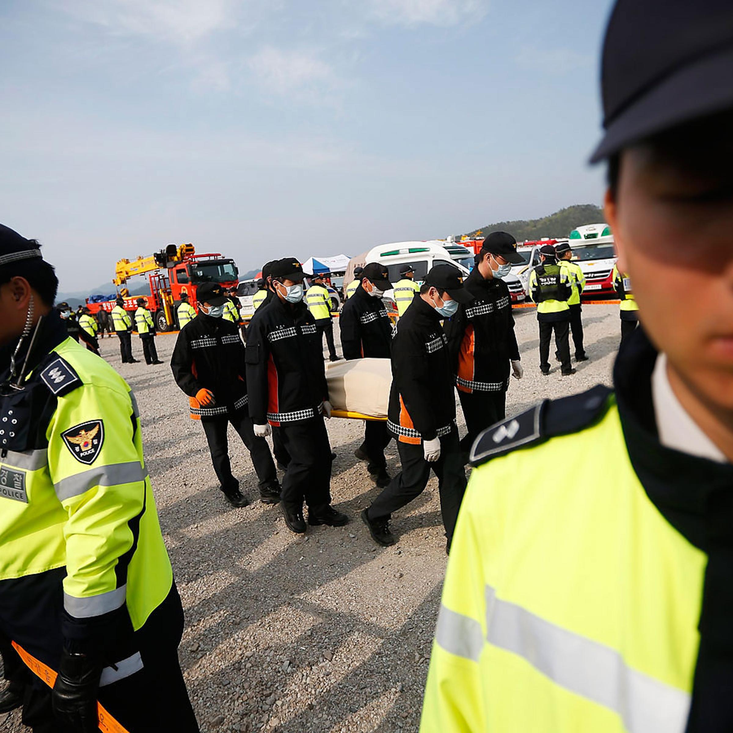 Rescue workers carry the body of passenger who was on the capsized Sewol passenger ship at a port where family members of missing passengers have gathered, in Jindo