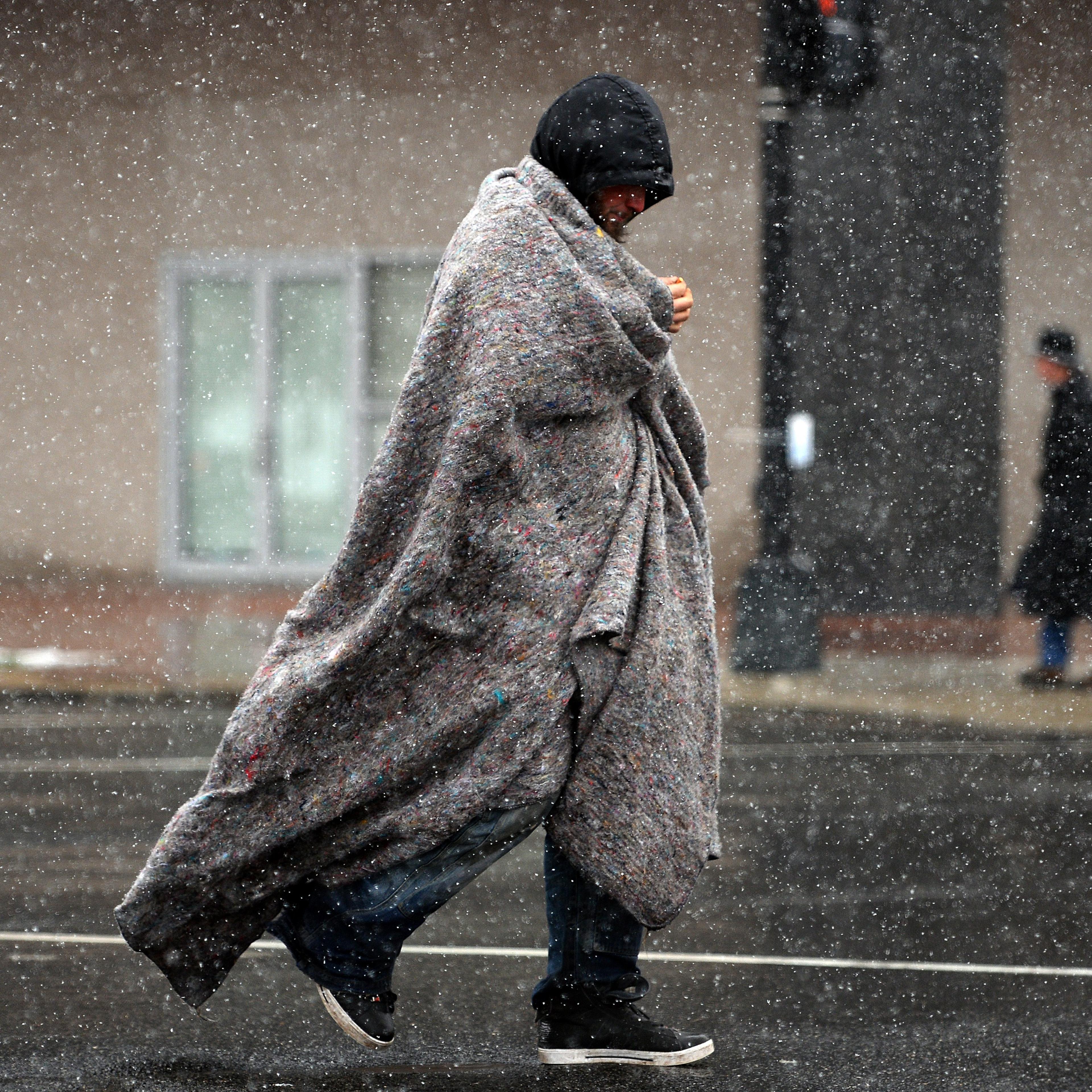 A man covers himself as he crosses a street under a snowfall in Washington, D.C. on March 25. 2014.