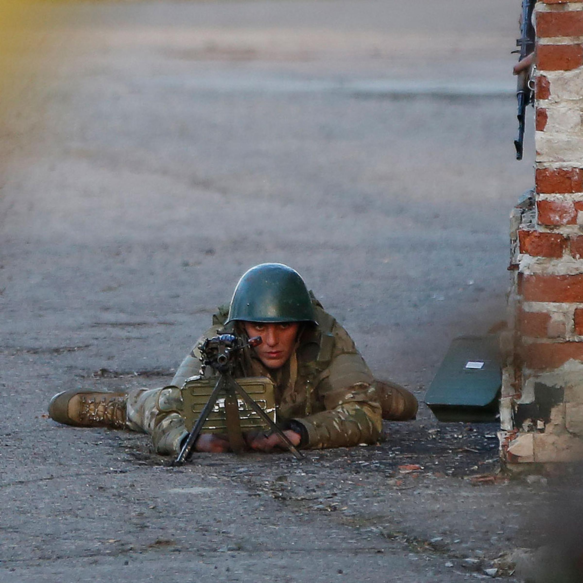 An Ukrainian soldier aims his weapon at pro-Russia protesters gathered in front of an Ukrainian airbase in Kramatorsk, in eastern Ukraine, April 15, 2014.