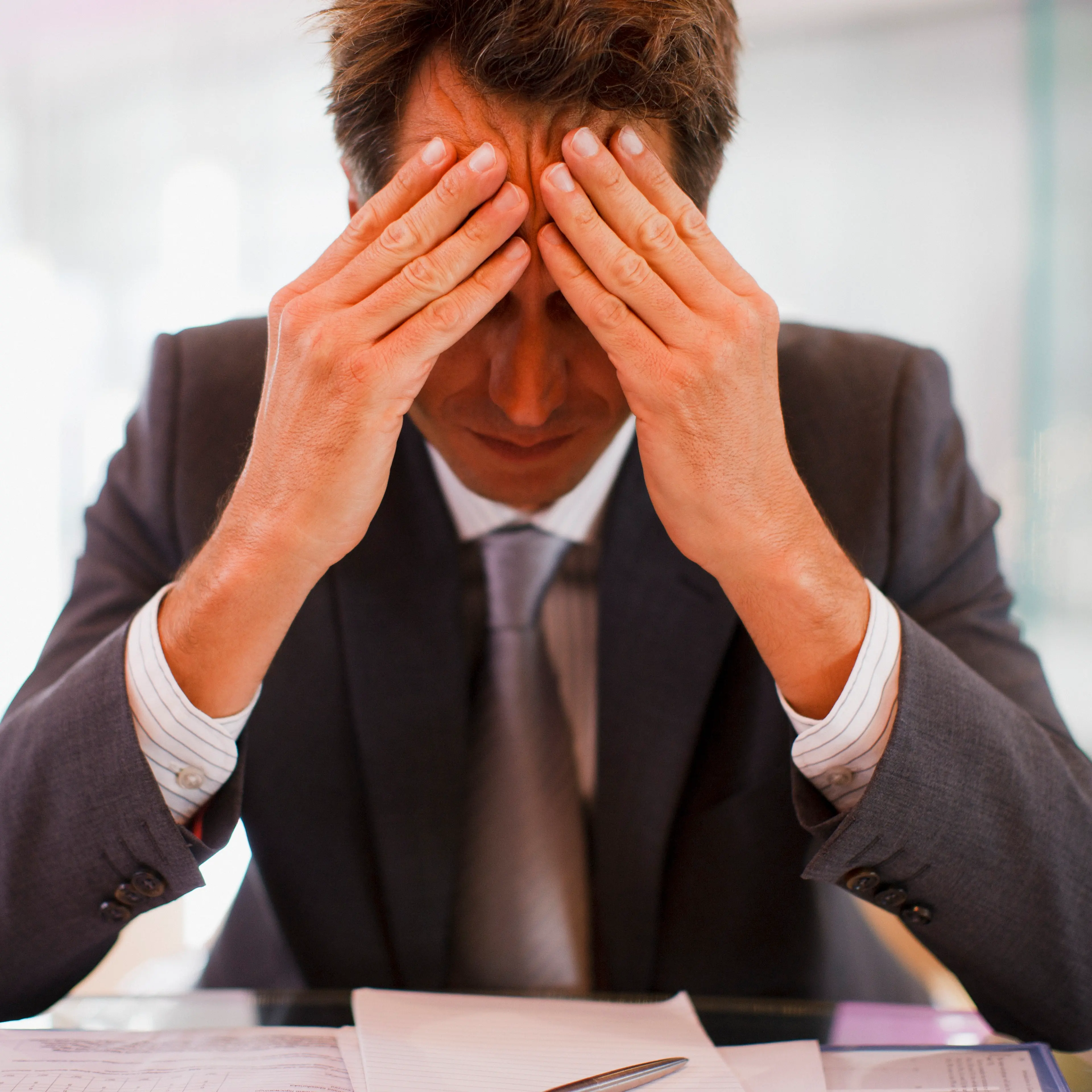 Frustrated businessman sitting at desk with head in hands