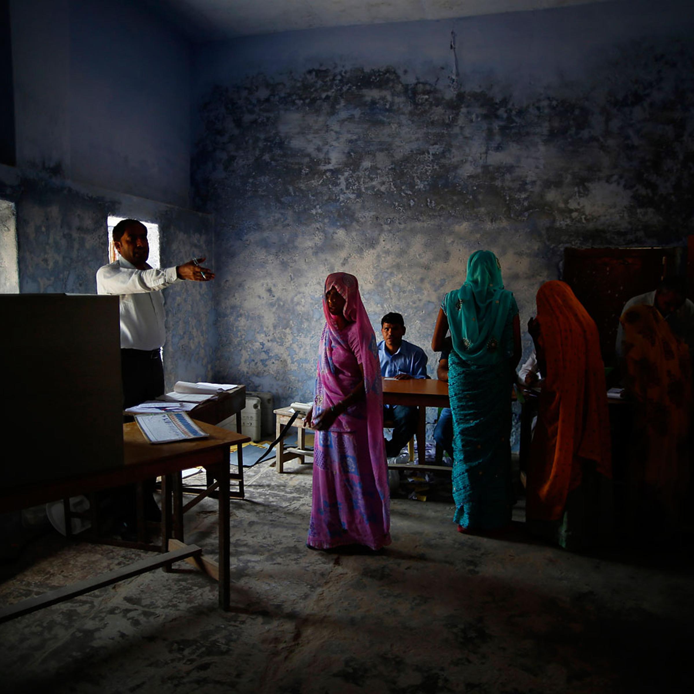 A woman voter is guided by an officer at a polling booth in Ujina, Haryana, India on April 10, 2014 for the crucial third phase of national elections.