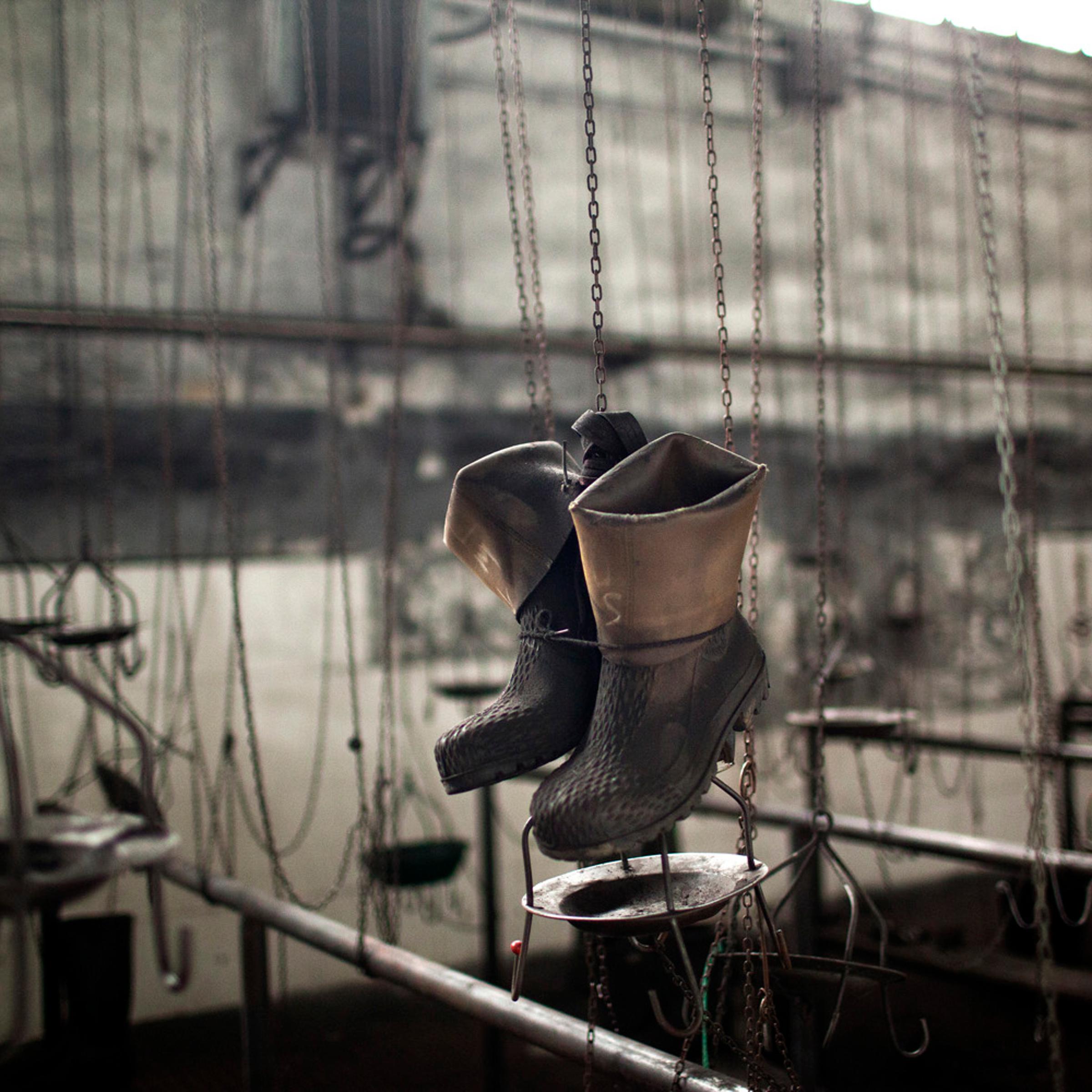 June 18, 2012. Boots hang in a changing room in the partially abandoned and closed Santiago mine, as a result of the coal crisis near Mieres, Oviedo, Spain.