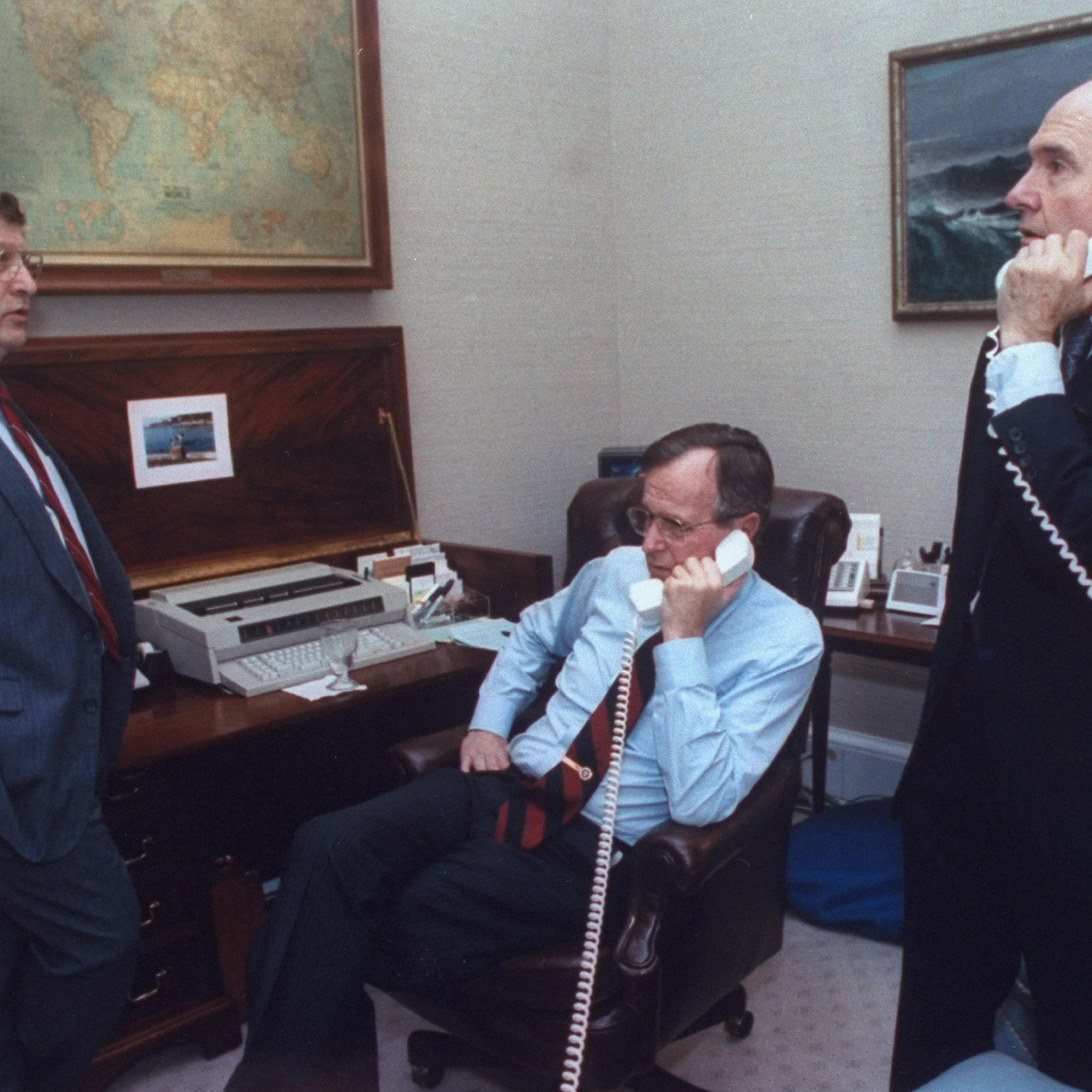 President George H.W. Bush on the phone with State Secretary Jim Baker during the gulf crisis, with White House Chief of Staff John Sununu & National Security Council Adviser Brent Scowcroft, at the White House in Washington on January 16, 1991.
