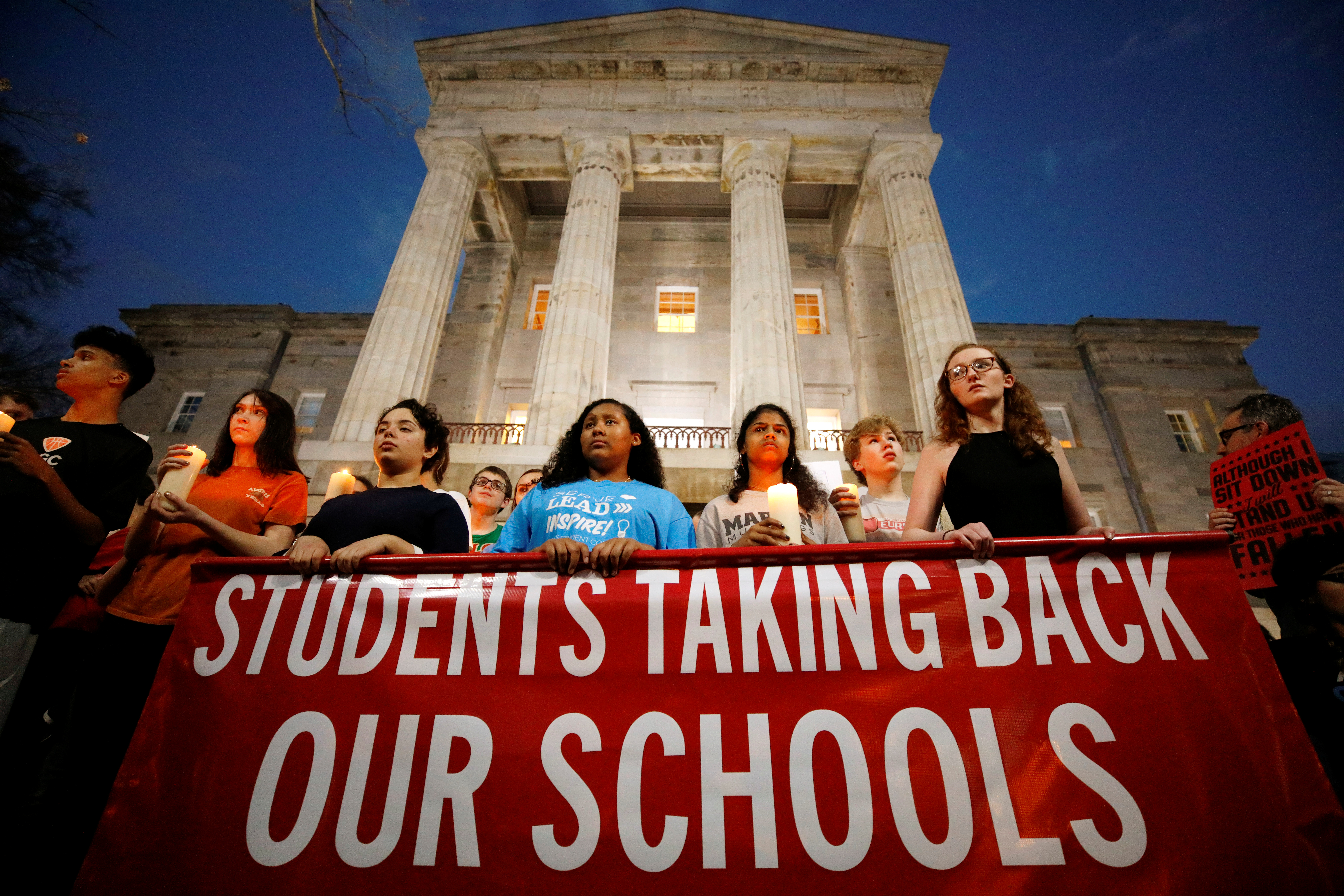 High school students hold candles in memory of the victims of the shooting at Marjory Stoneman Douglas High School as they stand in front of the North Carolina State Capitol building during a march for safer gun laws at dusk in Raleigh