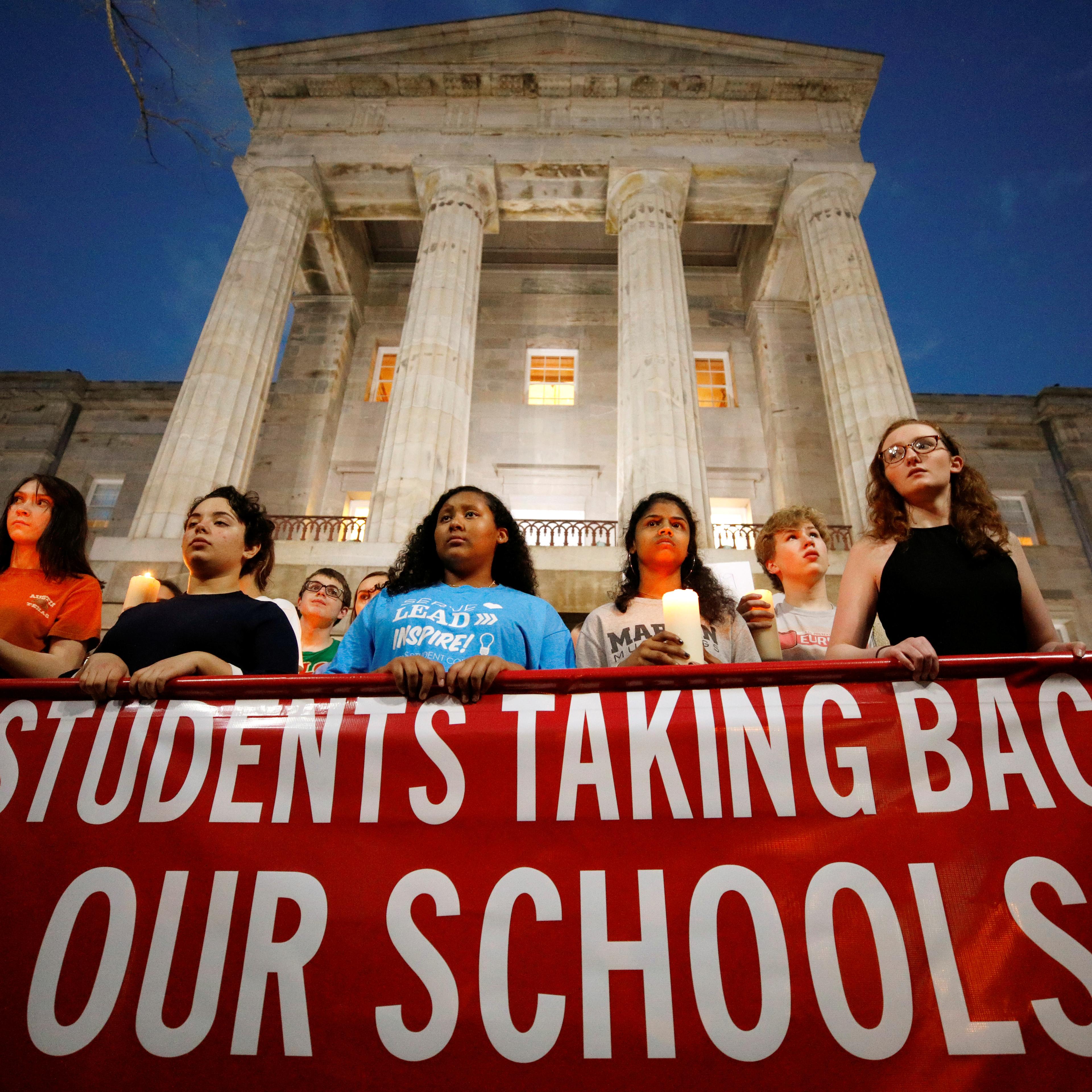 High school students hold candles in memory of the victims of the shooting at Marjory Stoneman Douglas High School as they stand in front of the North Carolina State Capitol building during a march for safer gun laws at dusk in Raleigh