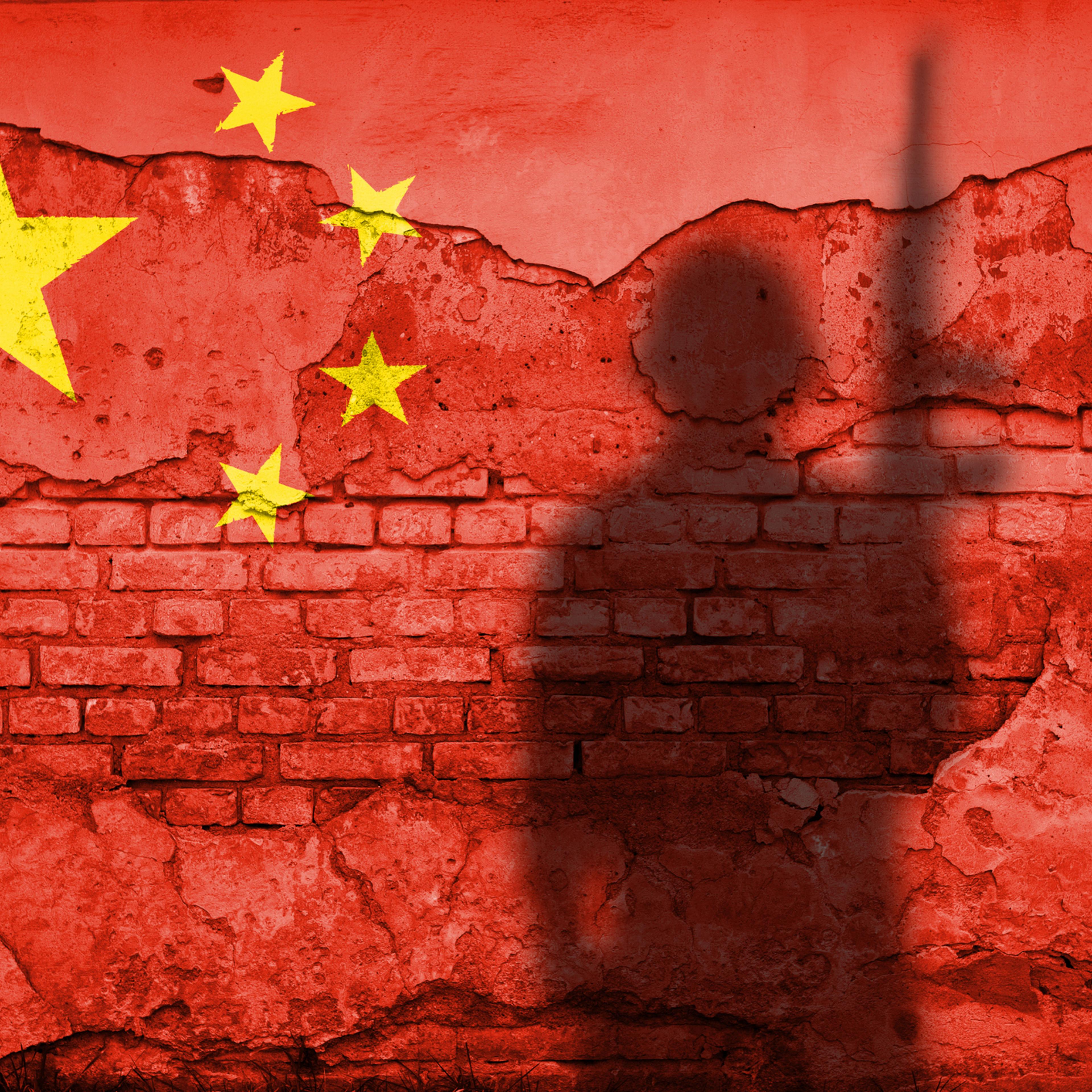 Flag of China painted on a concrete wall with soldier shadow
