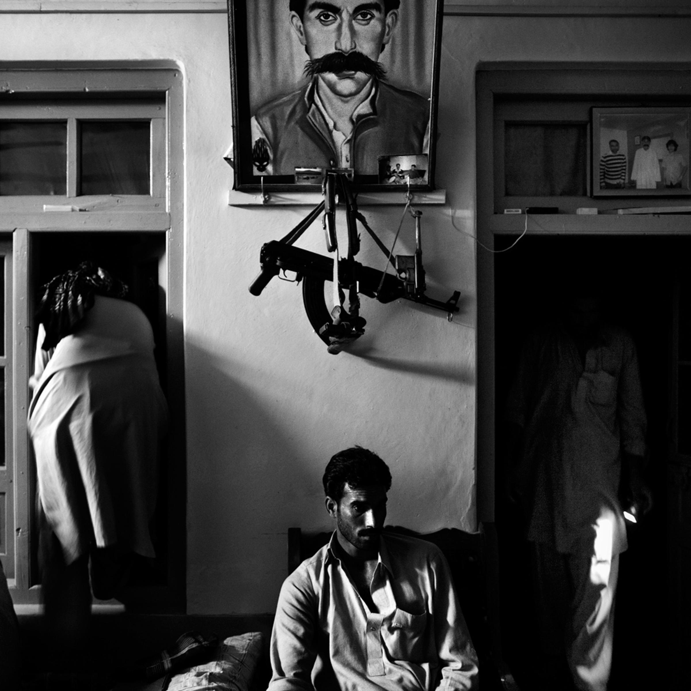 Pakistan, Swat Valley, Bara Bandai, November 2010. Lashkar members making preparations for pehra (night patrol) at the hujra of tribal elder Ahmed Khan, whose portrait is on the wall. In Pashtun culture a hujra is a place where tribal elders assemble to discuss different issues, sometimes holding meetings, called jirga, to settle any sort of dispute or evolve future strategies.