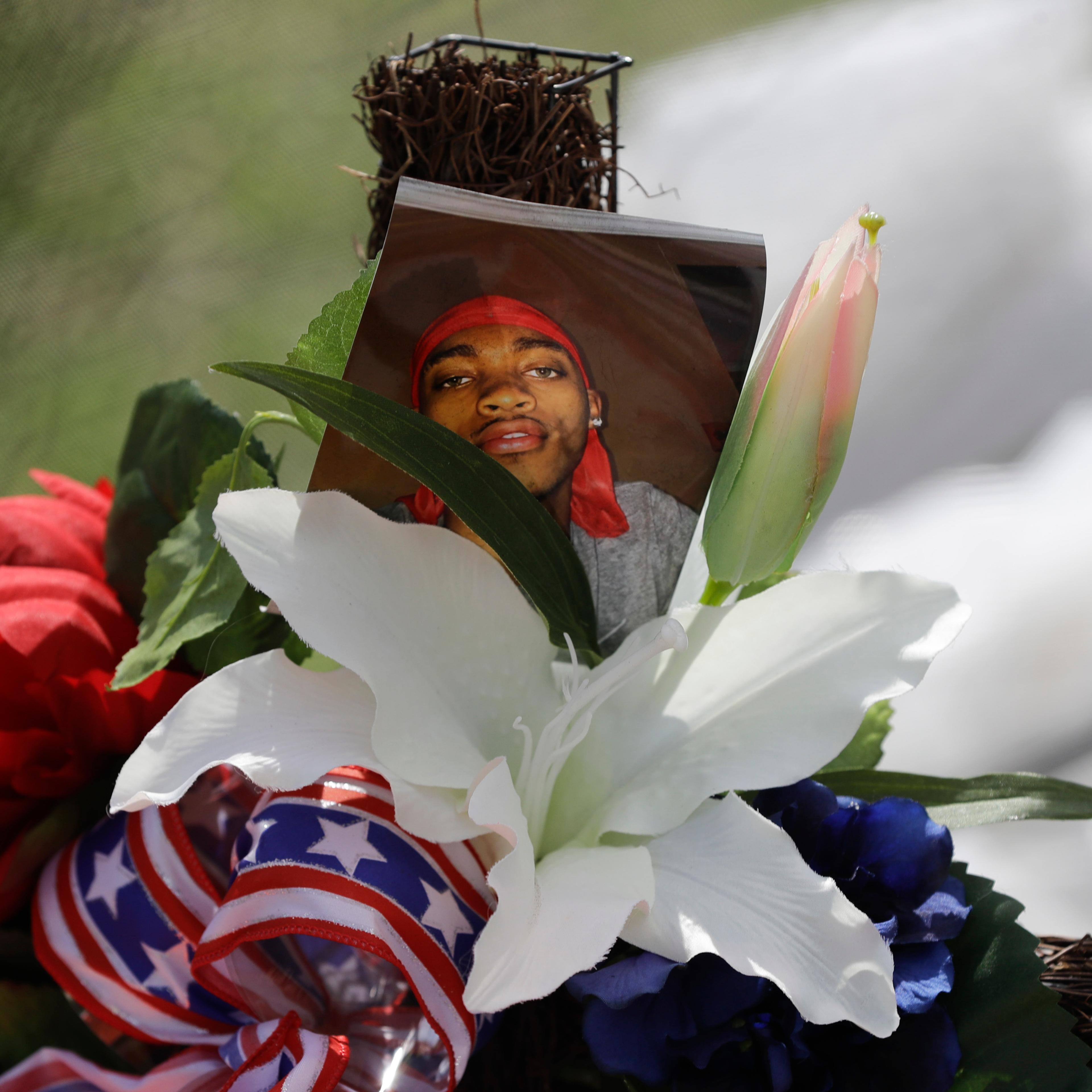 A photo of Dreasjon "Sean" Reed is placed in a memorial before a news conference