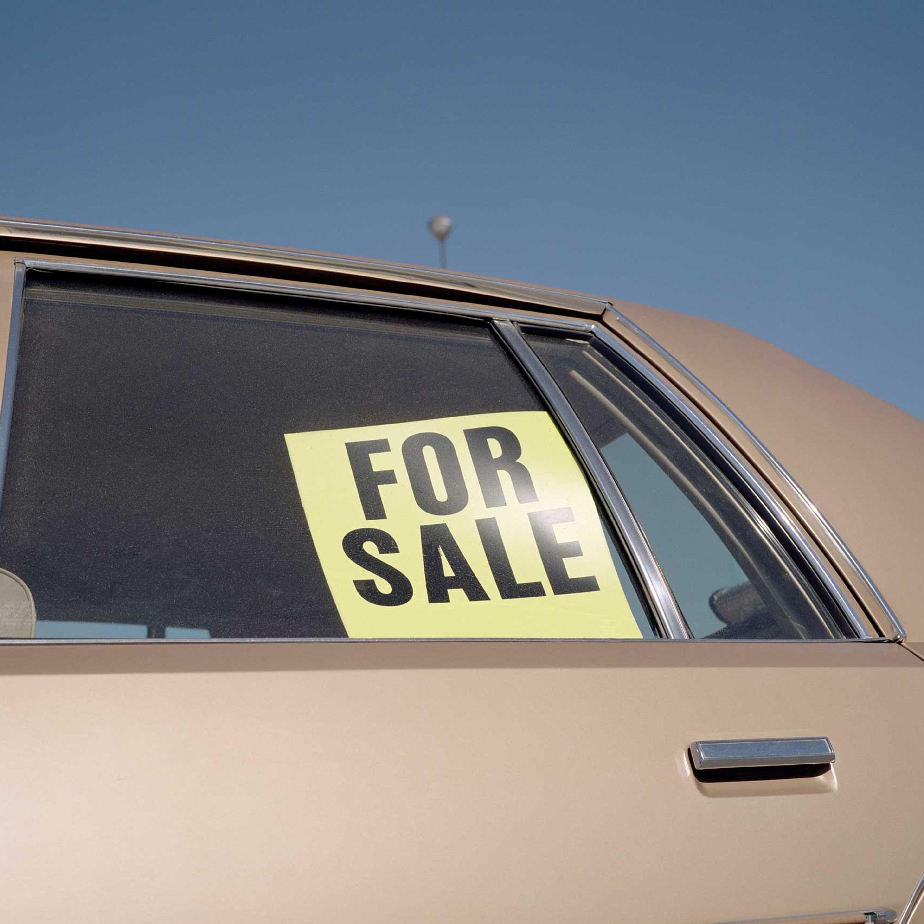 'For Sale' sign placed in car window, outdoors, close-up