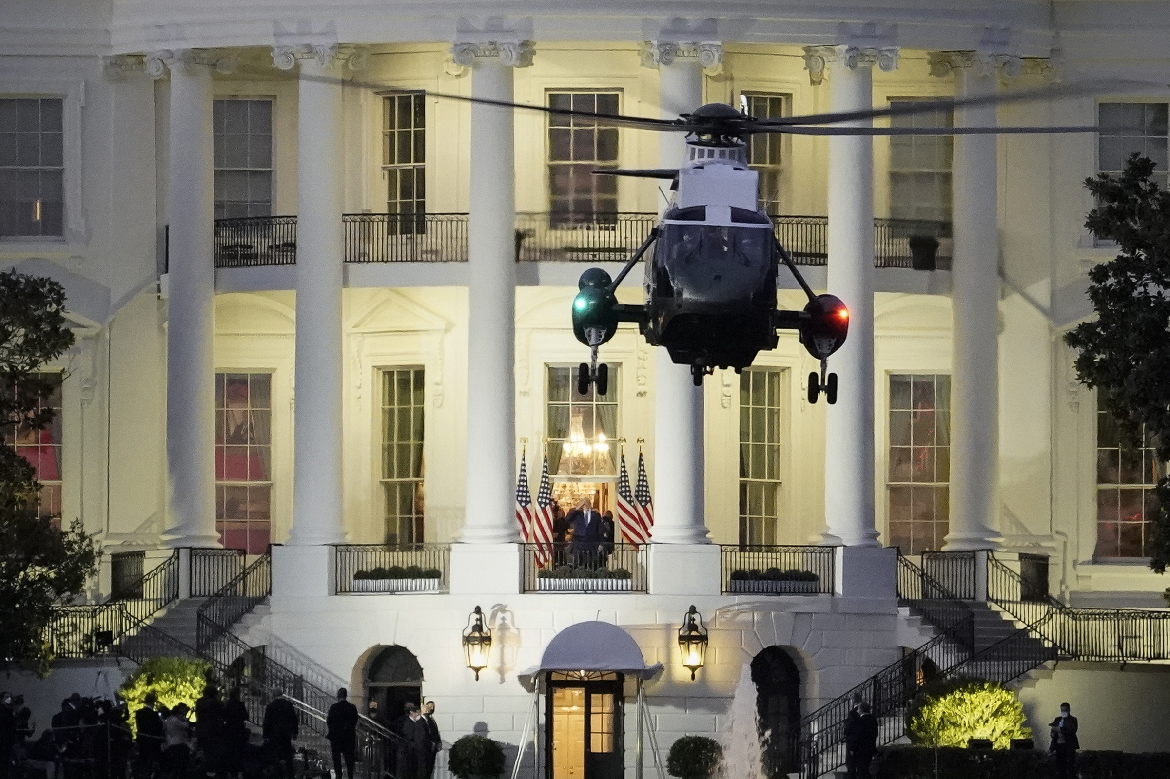 U.S. President Donald Trump stands on the Blue Room Balcony as Marine One takes off from the South Lawn of the White House on Oct. 5