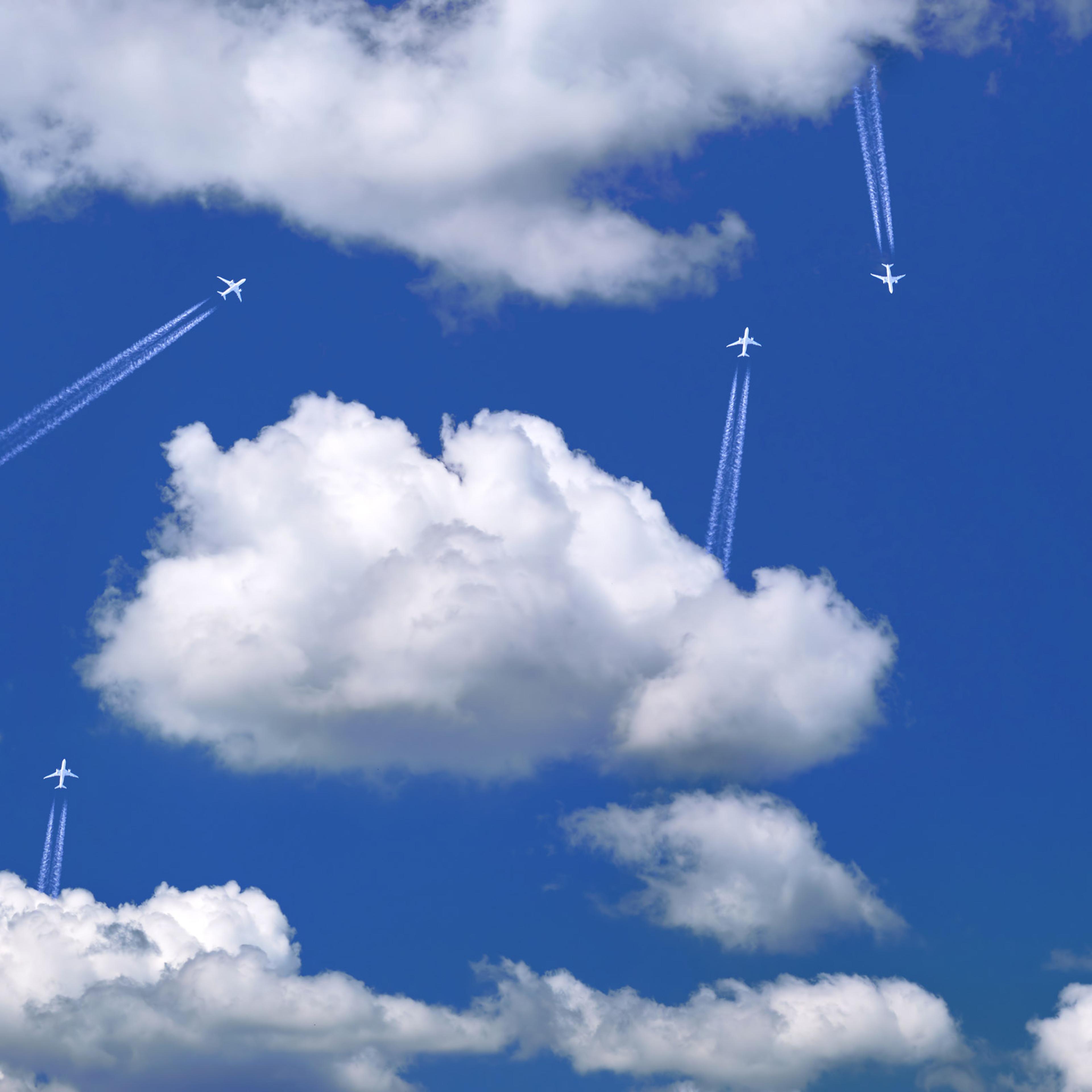 Many distant passenger jet planes flying on high altitude on clear blue sky leaving white smoke trace of contrail behind. Busy air transportation concept
