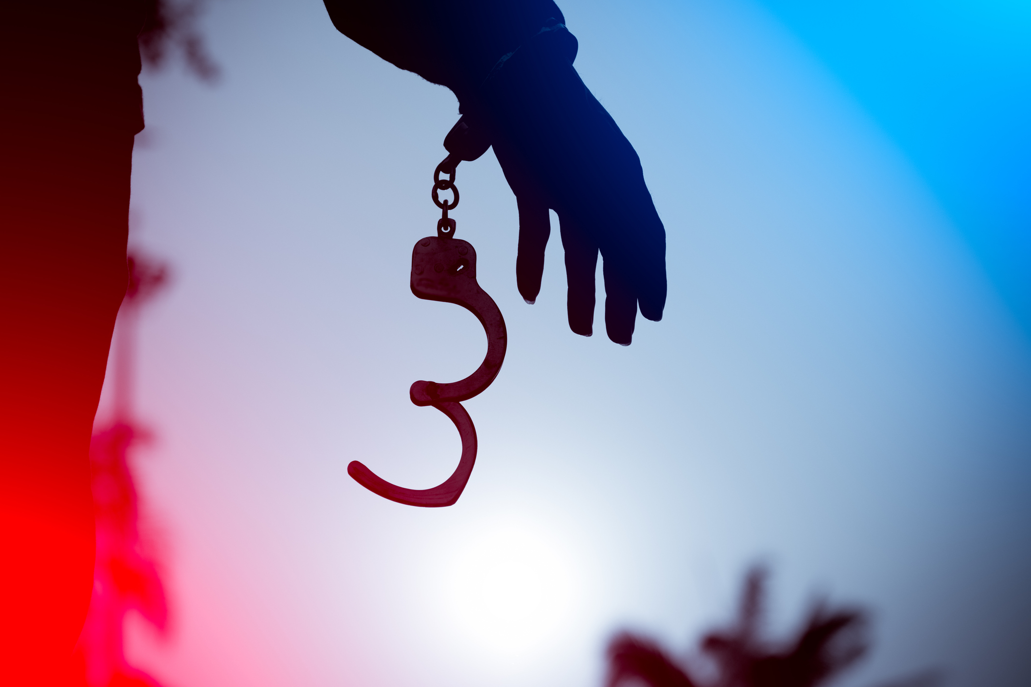 A prisoner behind bars with hands cuffed