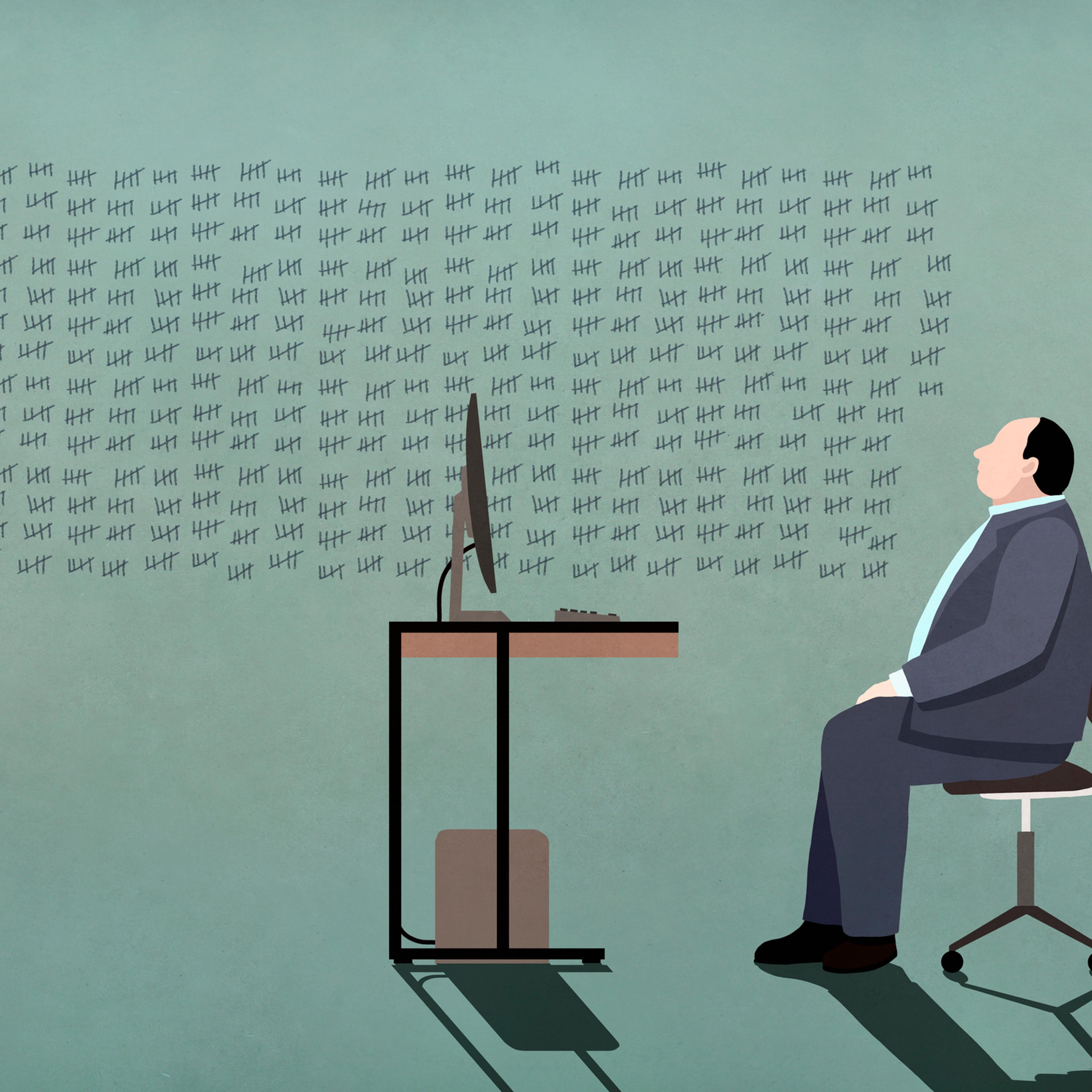 Businessman at computer looking at tally marks on wall