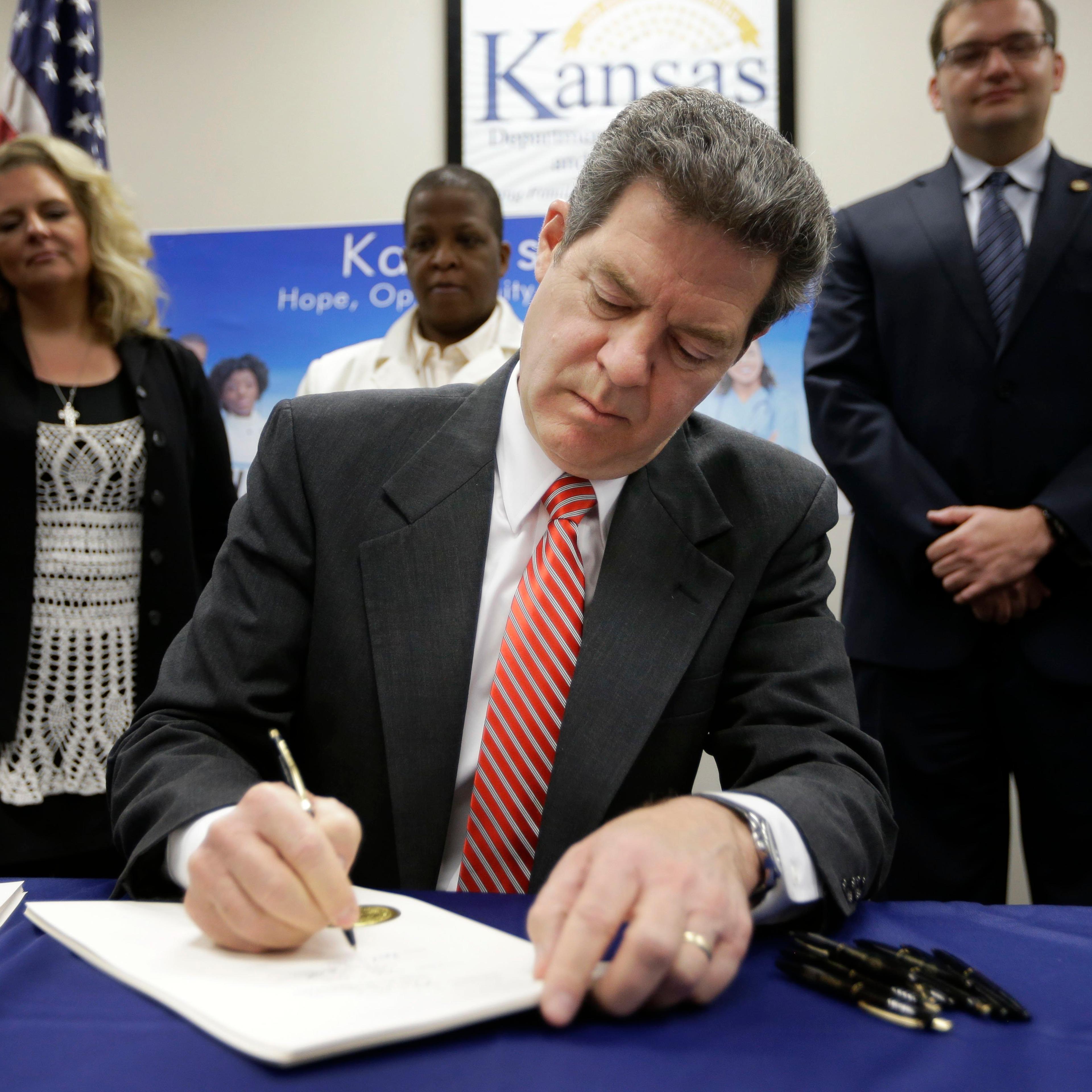 Gov. Sam Brownback signs a welfare reform bill into law in Topeka, Kan. on April 16, 2015.